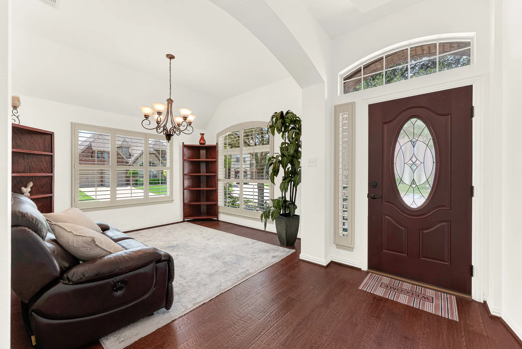 A soaring ceiling, graceful archways, and an elegant front door create a bright, welcoming first impression, while plantation shutters fill the space with soft natural light. It's an inviting spot to greet guests or unwind with a favorite book before the day begins.