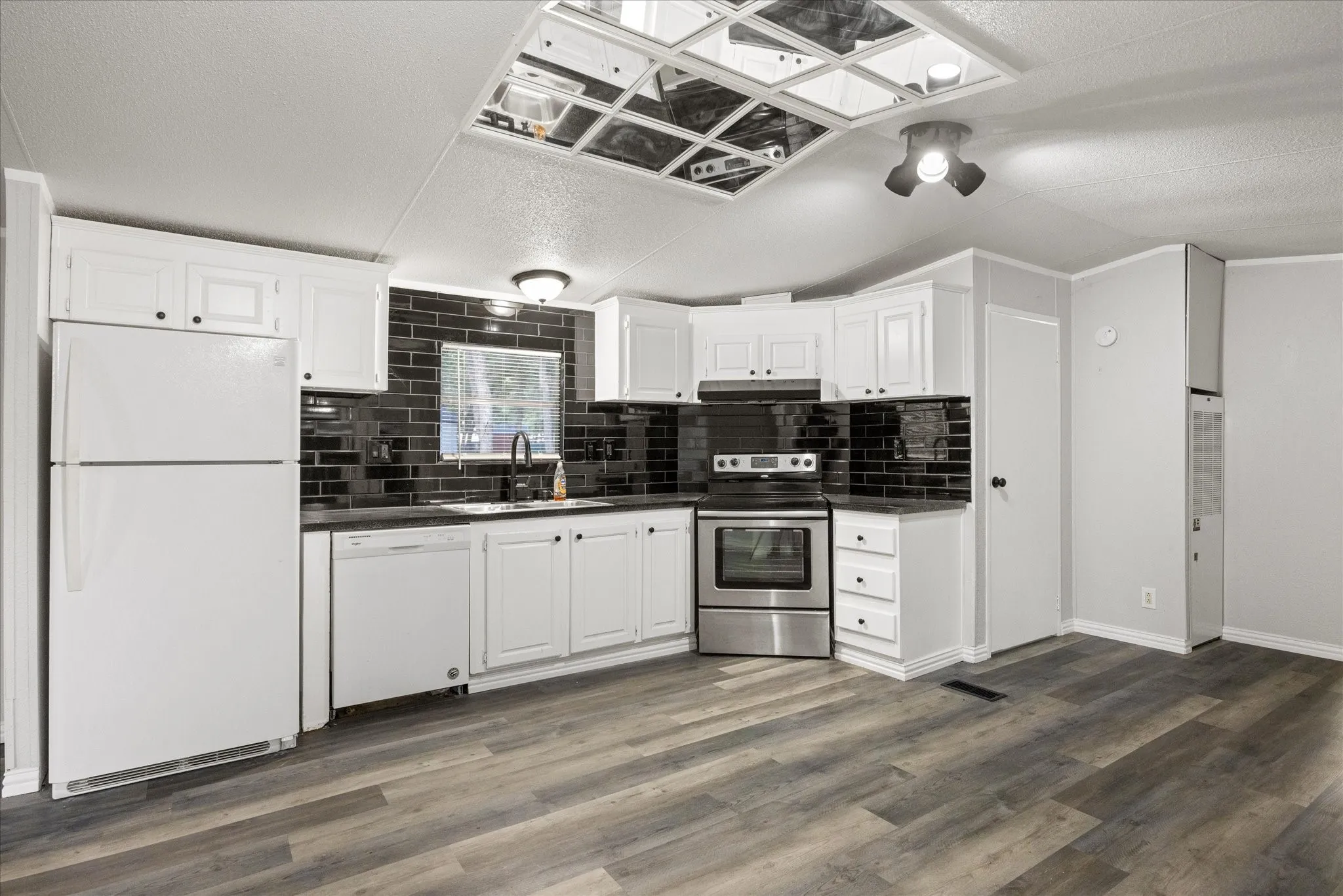 4617 Lyndi Ln
Granbury, TX  76049 Kitchen featuring white cabinetry, dark subway tile backsplash, stainless steel range, and wood-finish flooring