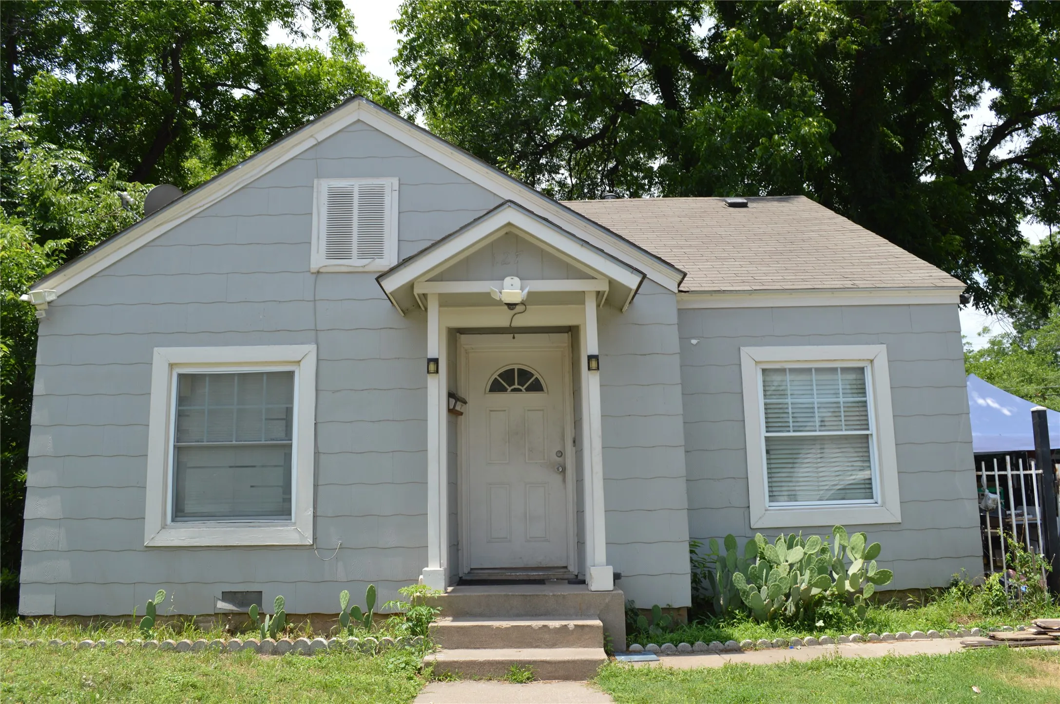 Single-story residence featuring light gray horizontal siding and a gabled roofline