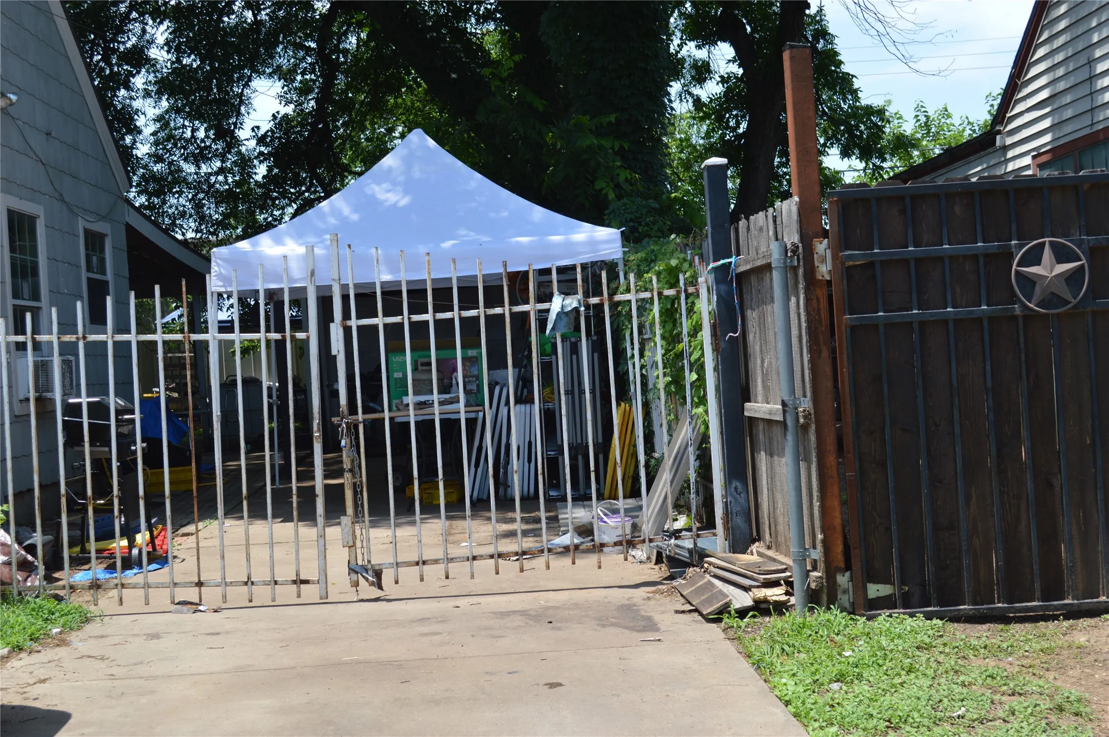Gated property access featuring a wrought iron gate and a dark wood privacy fence with a decorative metal star accent