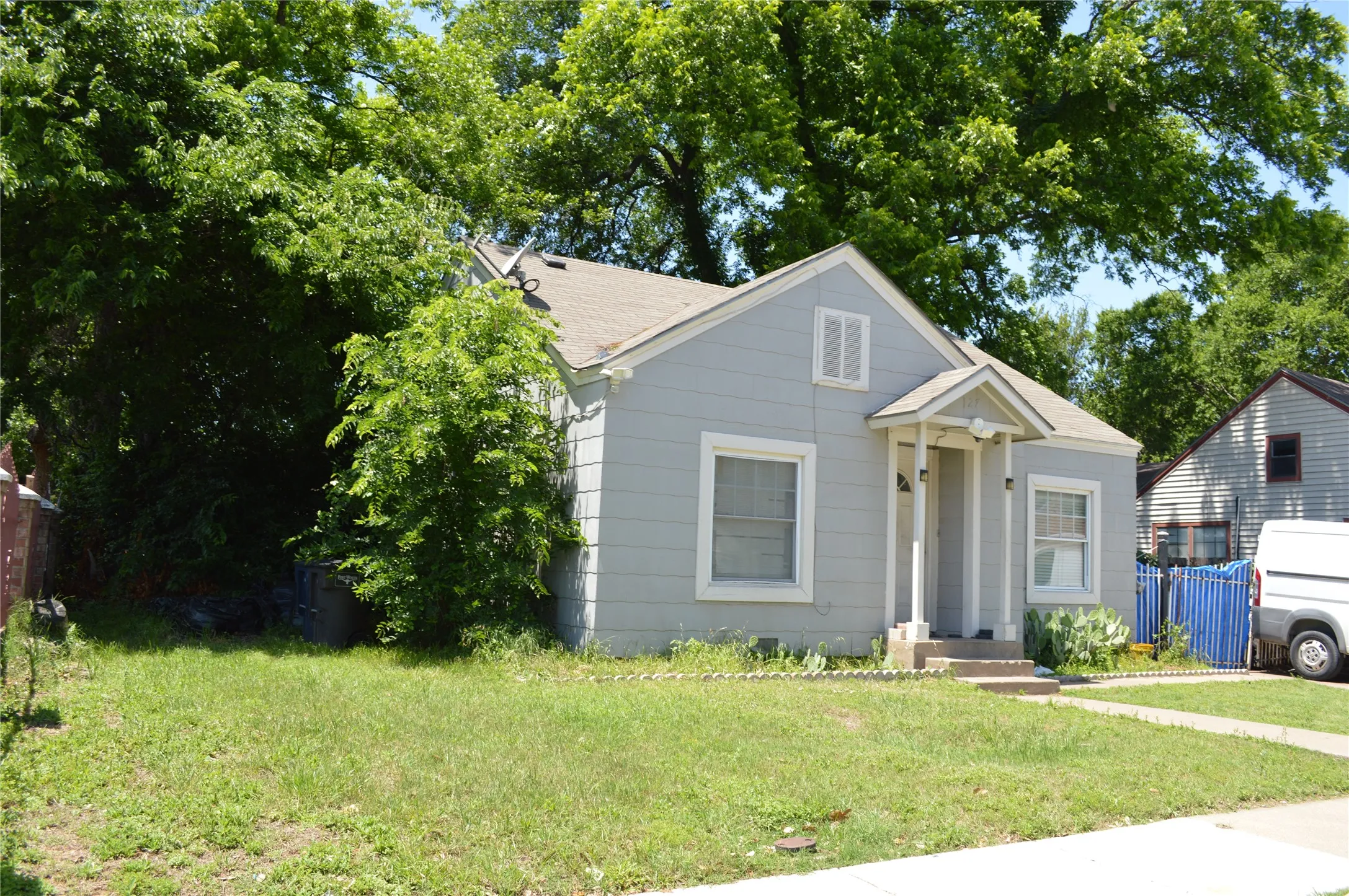 Single-story residence featuring a light gray facade, white trim, and a gabled roofline