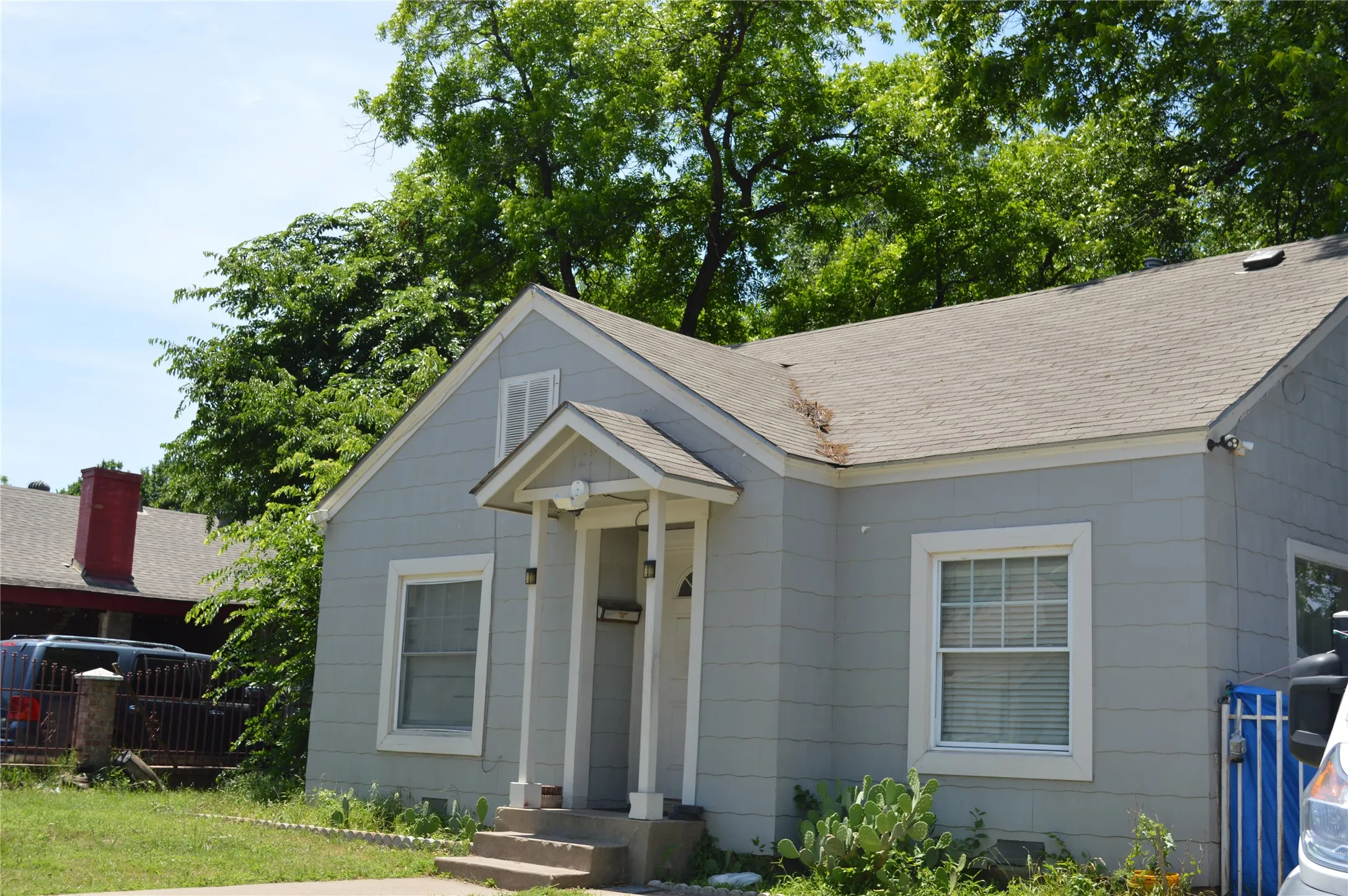 Light gray siding exterior with white trim windows and a covered front porch featuring white columns