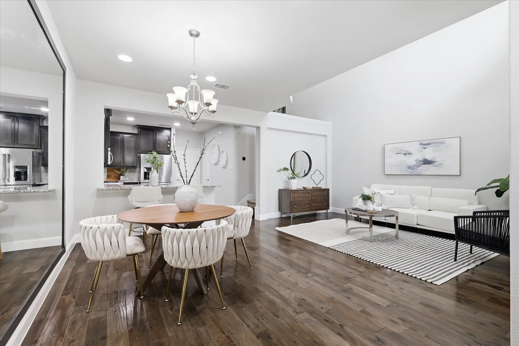 Open-concept living space featuring wood-finish flooring, a vaulted ceiling, recessed lighting, and a kitchen pass-through with granite countertops and dark wood cabinetry