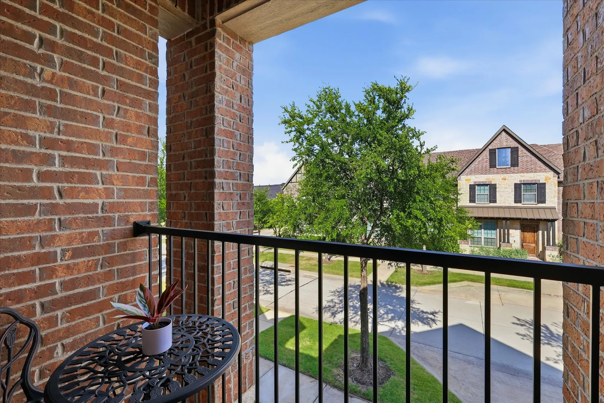 Balcony featuring a black wrought iron railing, traditional brick column, and matching brick wall