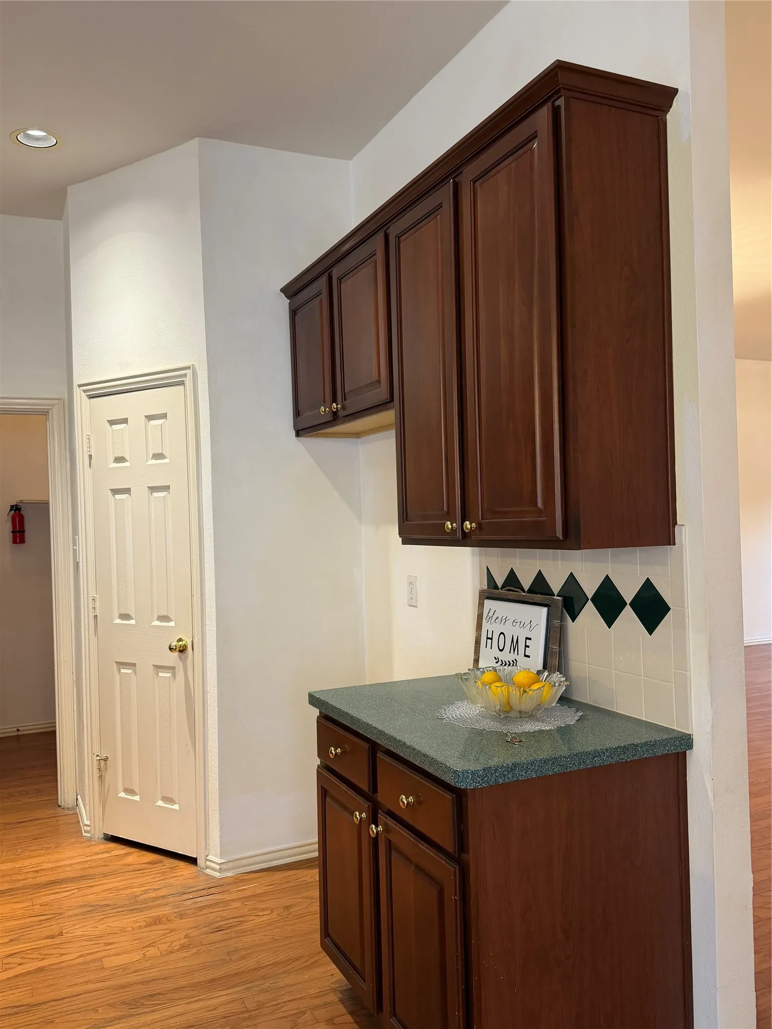 Custom cabinetry with crown molding, a green speckled countertop, and a tiled backsplash with diamond accents