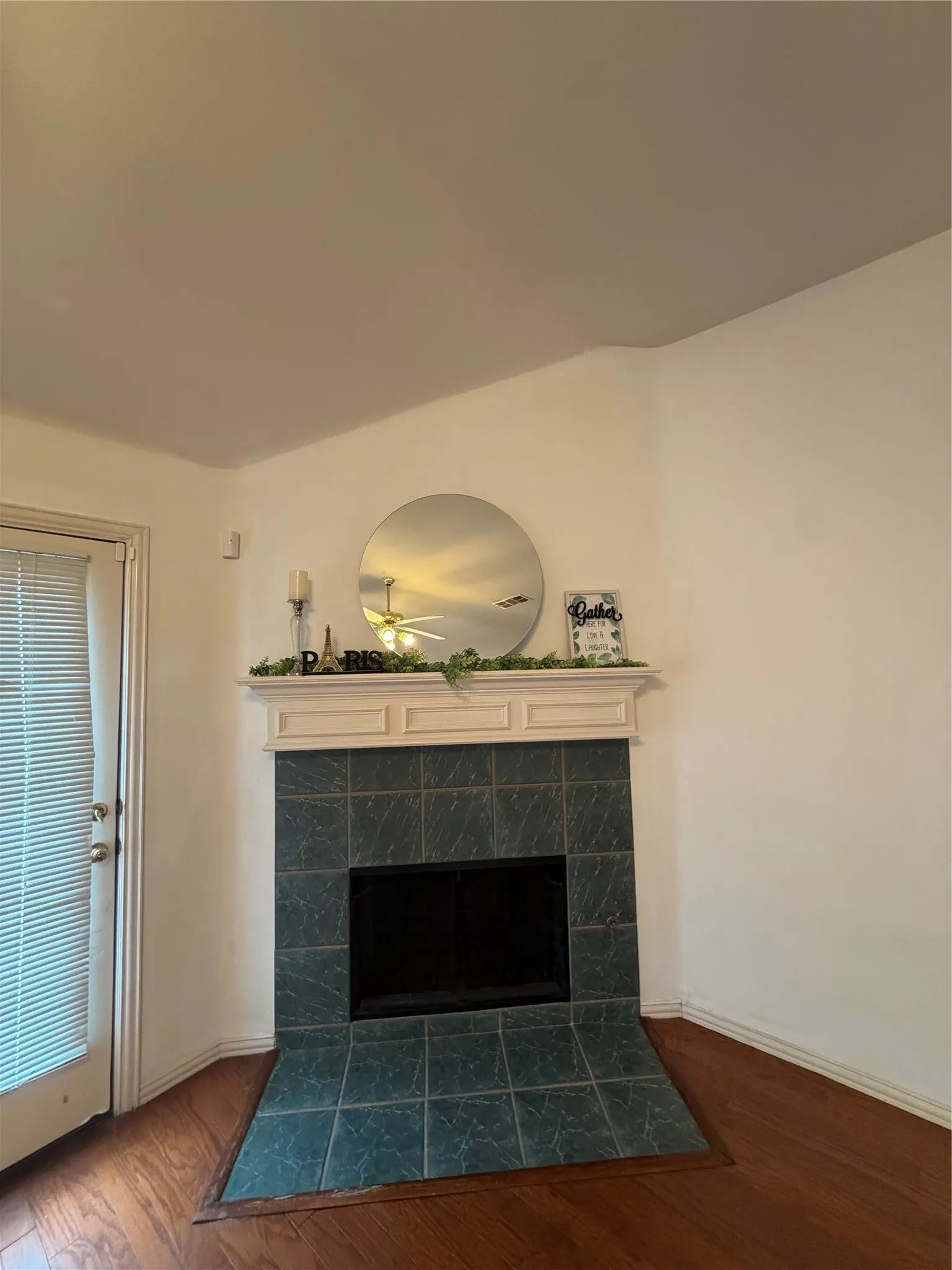 Corner fireplace with a white mantel, dark teal tile surround, and tile hearth