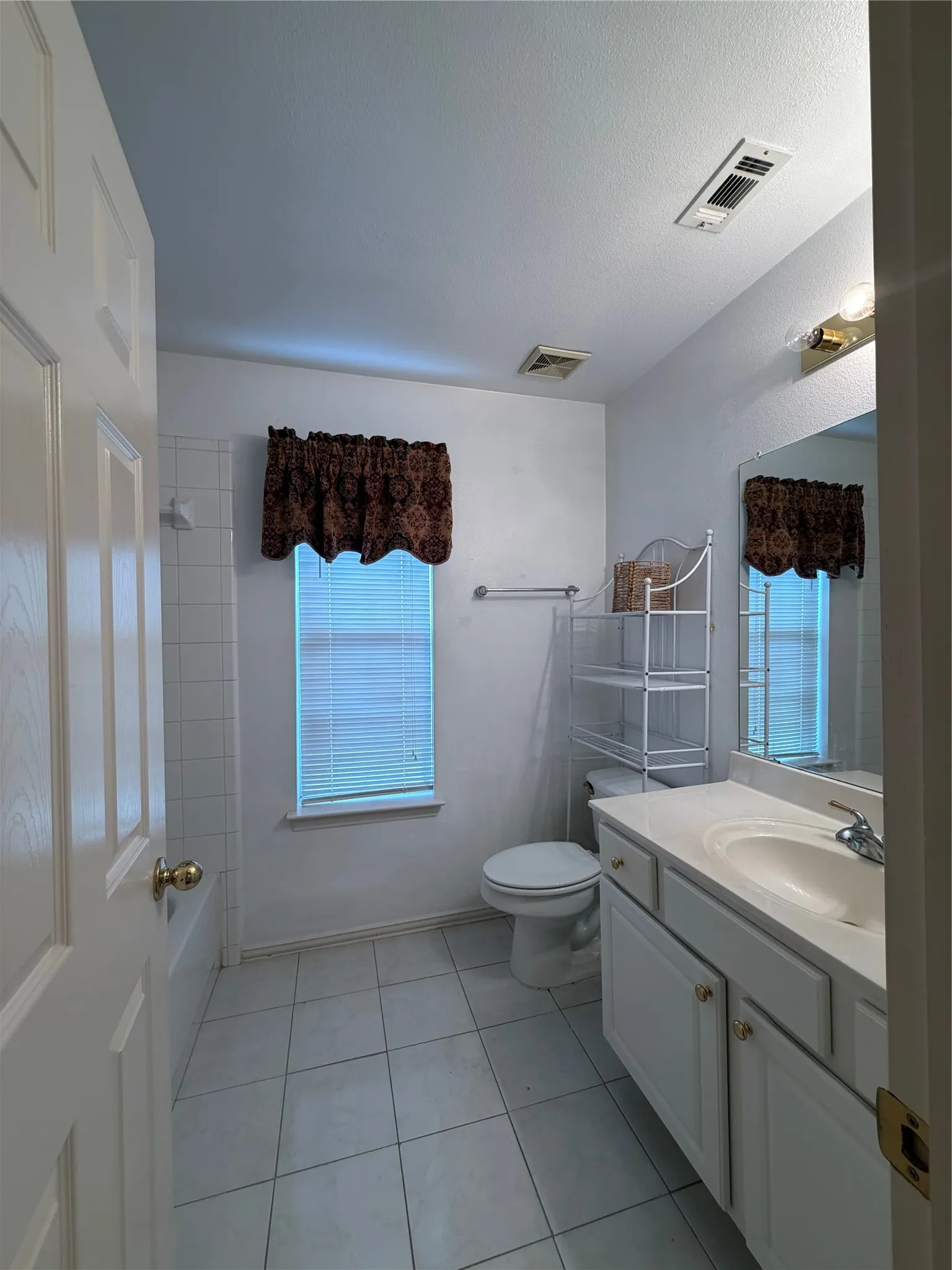 White tile flooring with a window featuring horizontal blinds