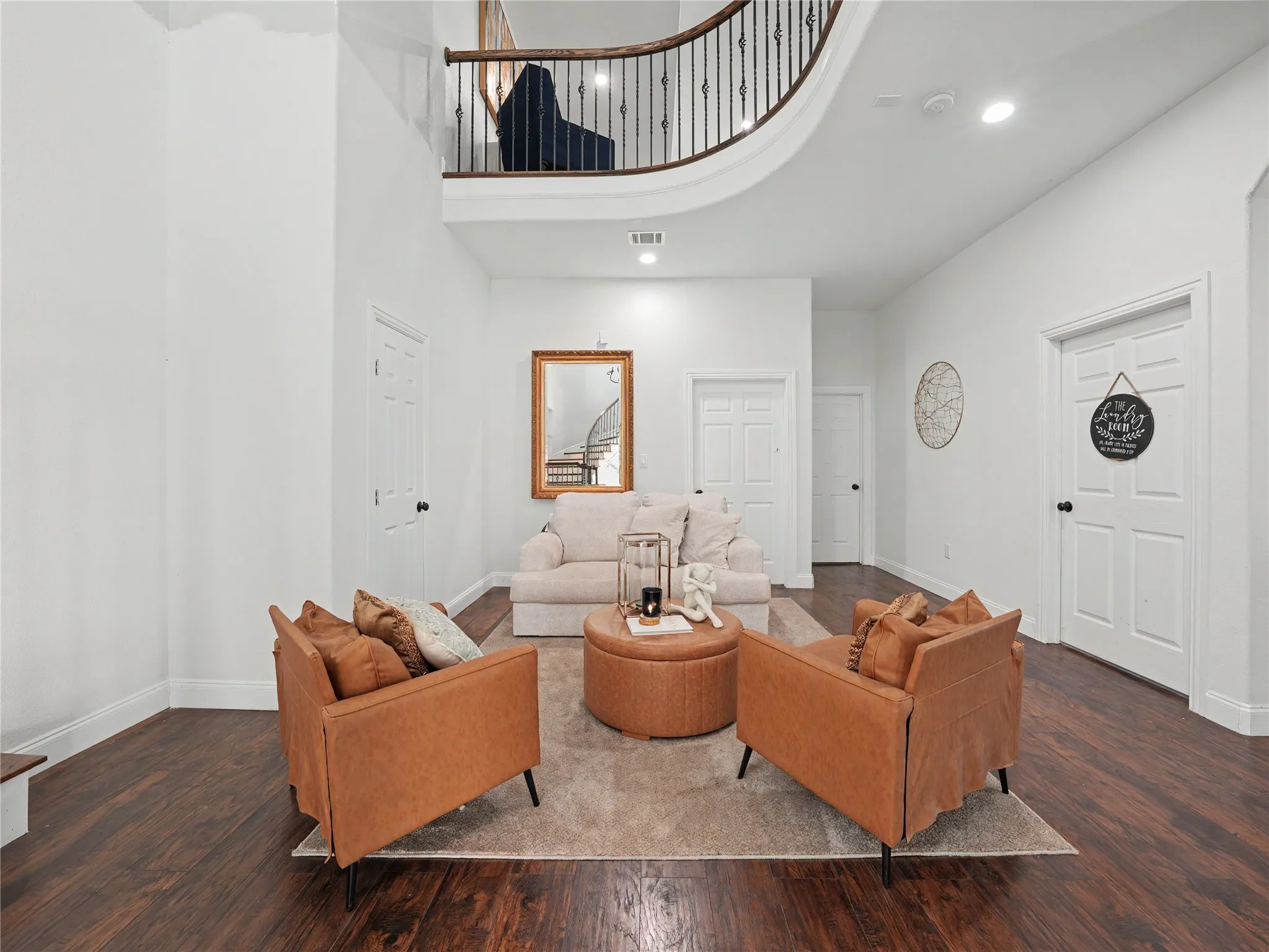 Double-height entry foyer featuring a curved staircase with wrought iron balusters and wood handrail