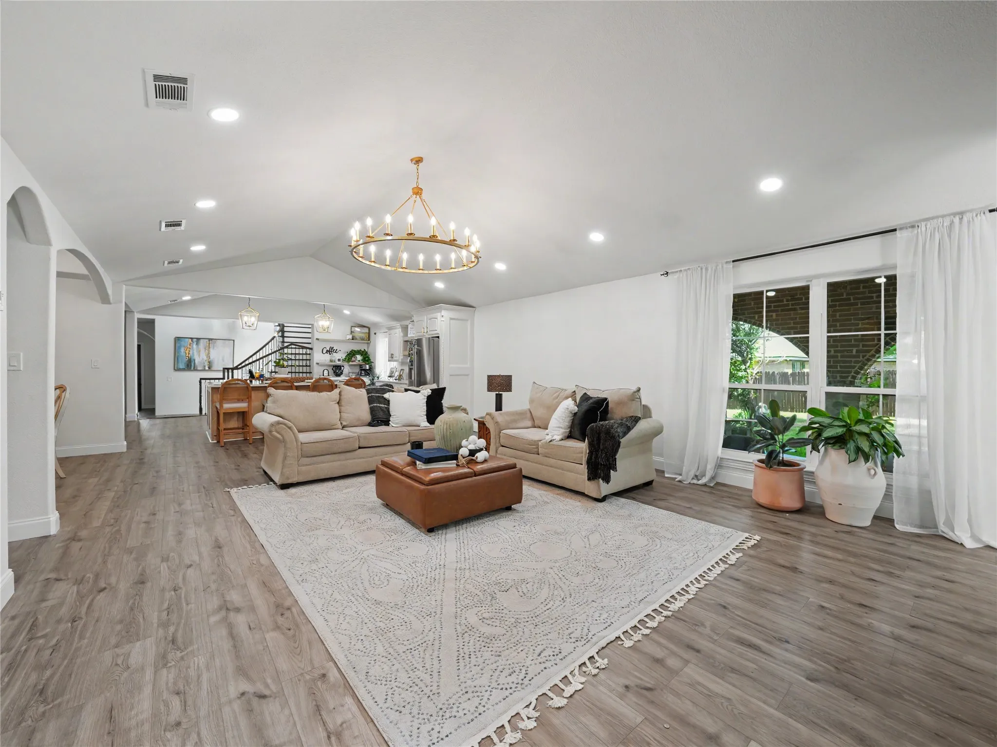 Spacious living area featuring wood-finish flooring, recessed lighting, and a prominent chandelier