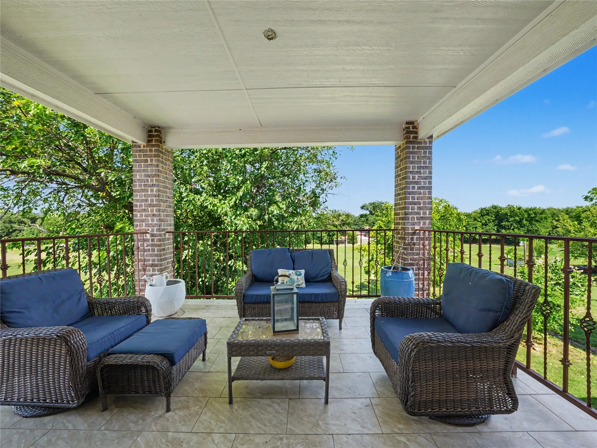 Covered patio featuring brick support columns, a metal railing, and tile​​‌​​​​‌​​‌‌​‌‌​​​‌‌​‌​‌​‌​​​‌​​ flooring