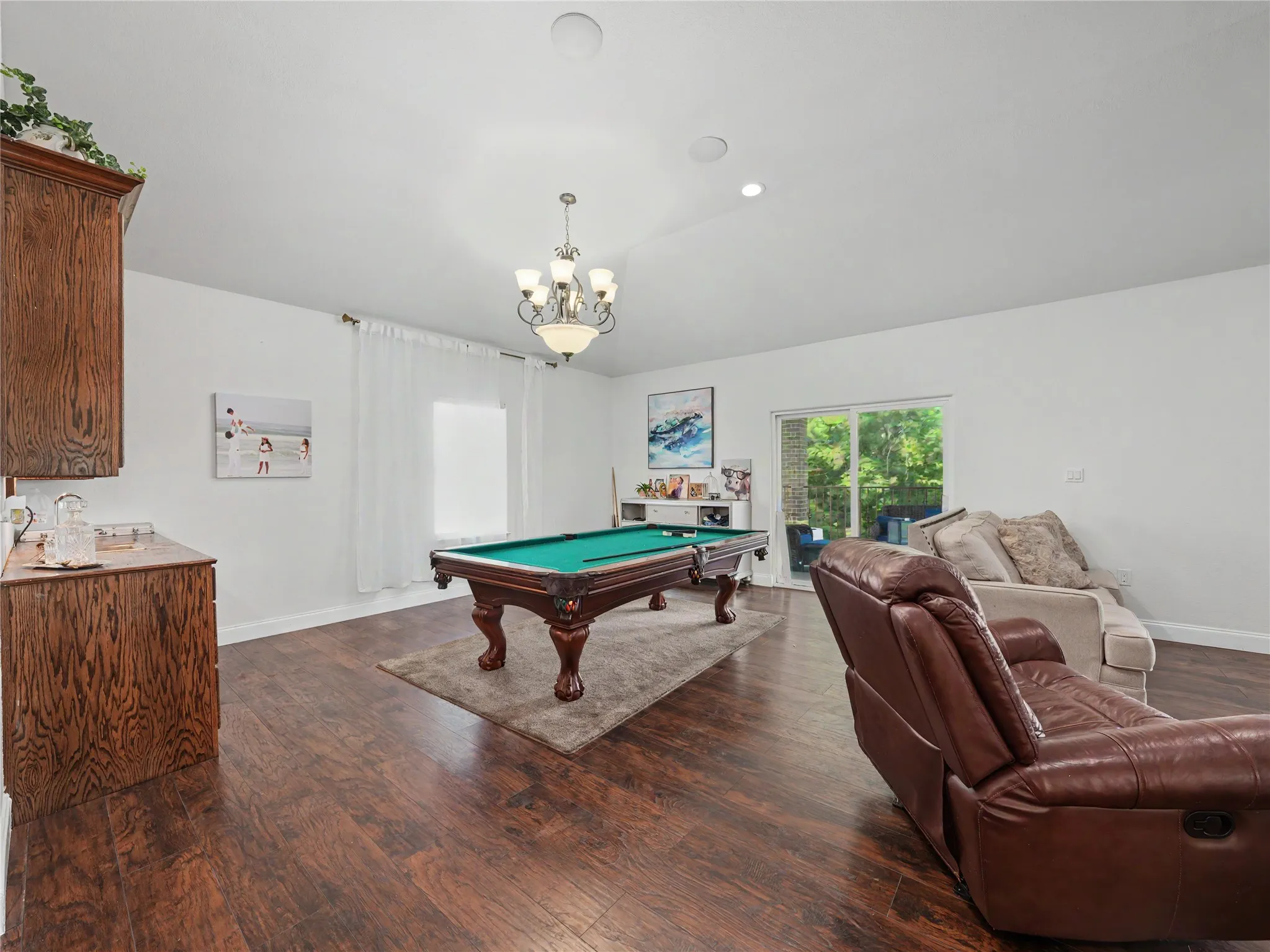 Spacious room with wood-finish flooring, recessed lighting, and a chandelier