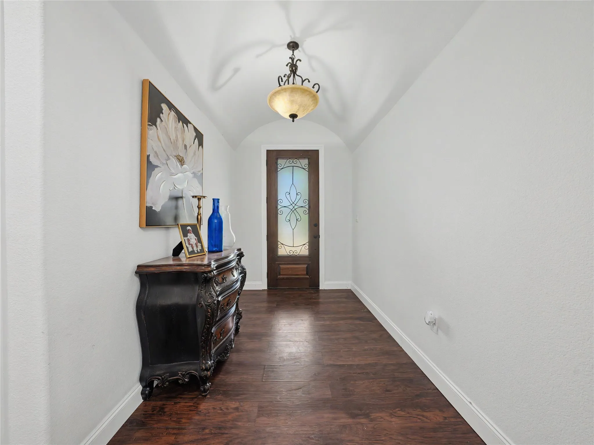 Entryway featuring a wood-finish floor, arched ceiling, and decorative chandelier