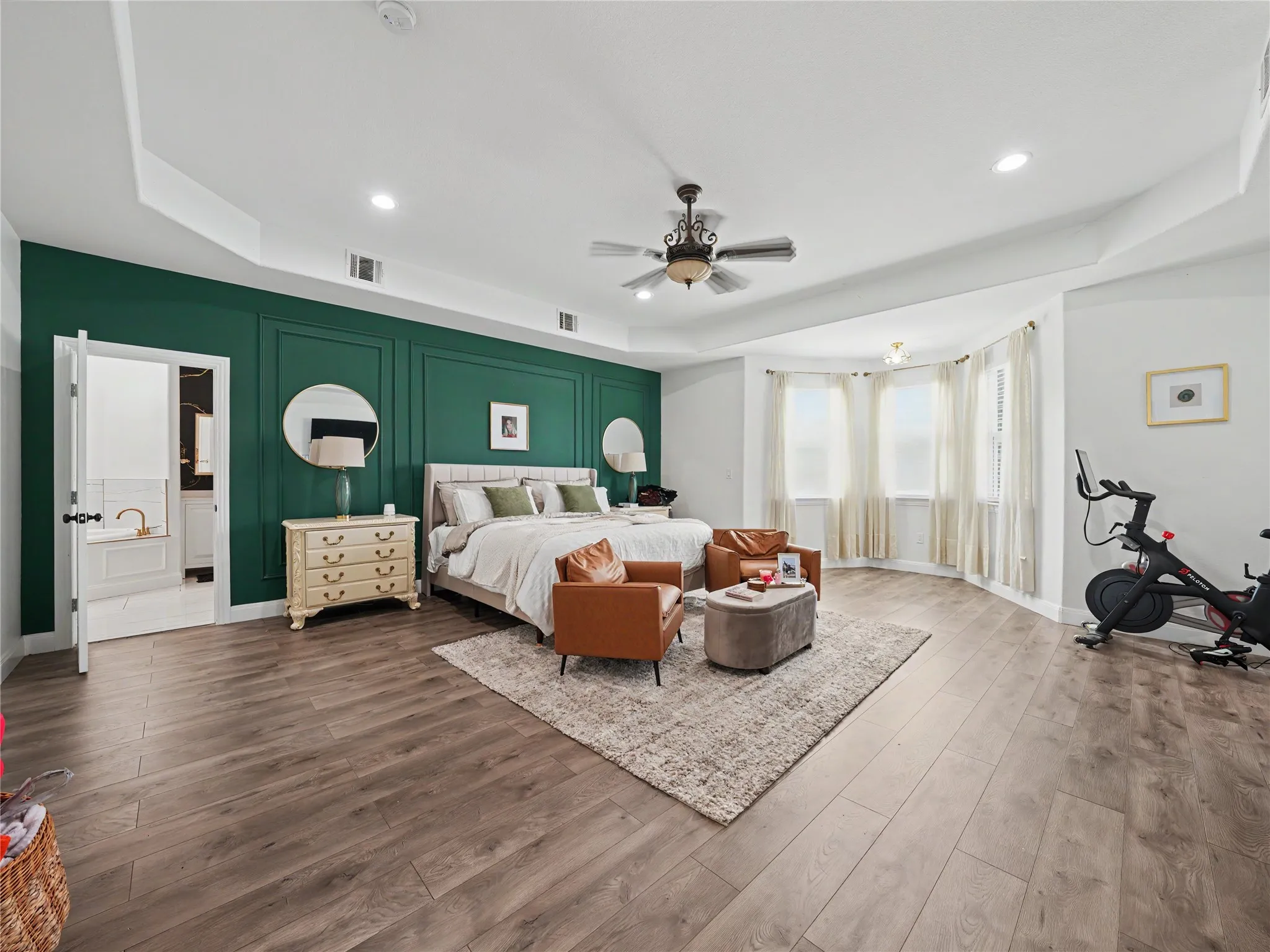Spacious bedroom with wood-finish flooring, a tray ceiling, and a large bay window