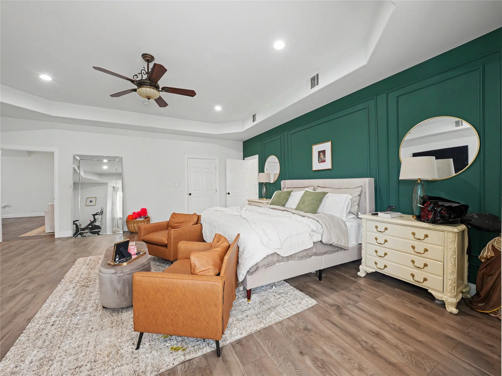 Spacious room featuring wood-finish flooring, a tray ceiling with recessed lighting, and a ceiling fan