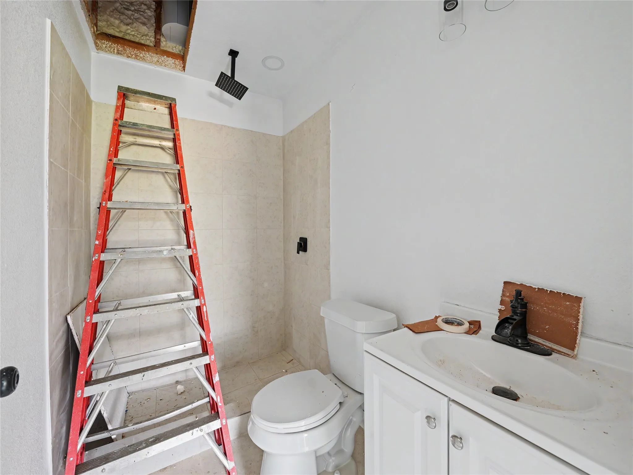 Bathroom with a white vanity and integrated sink, a toilet, and light-toned wall tiling