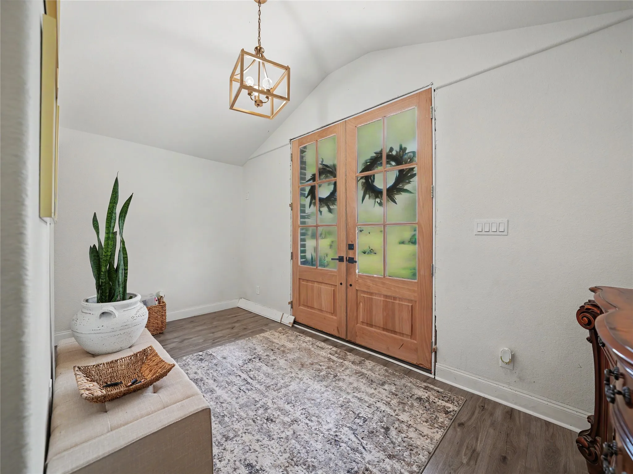 Vaulted entry with wood-finish flooring and a contemporary geometric chandelier