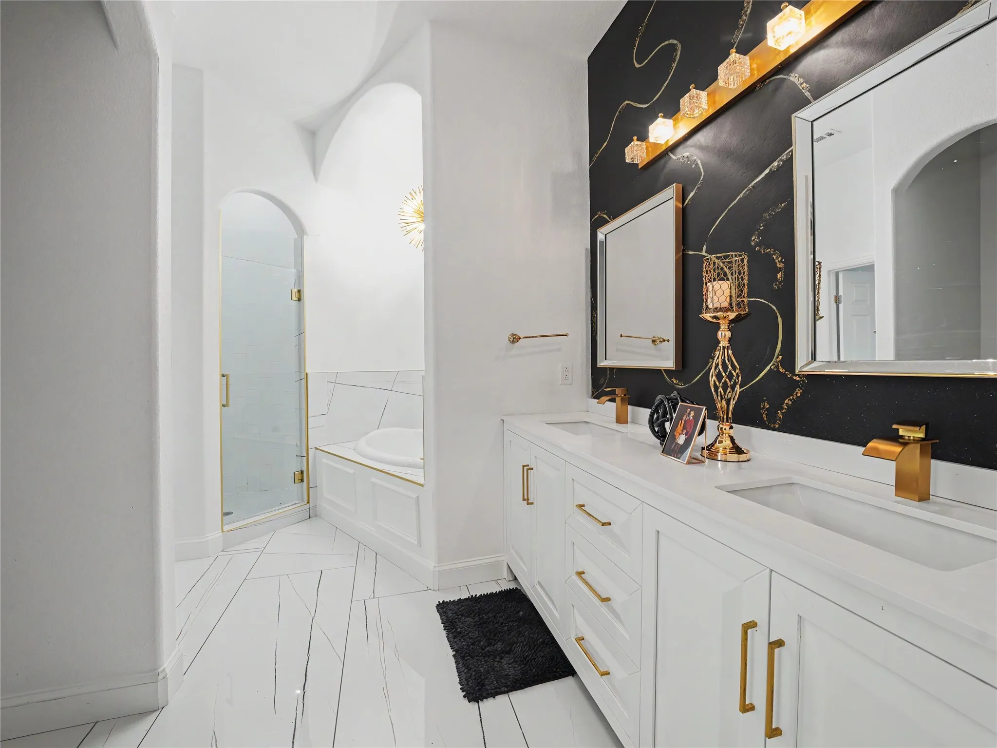 Dual vanity with white cabinetry, gold hardware, and integrated sinks