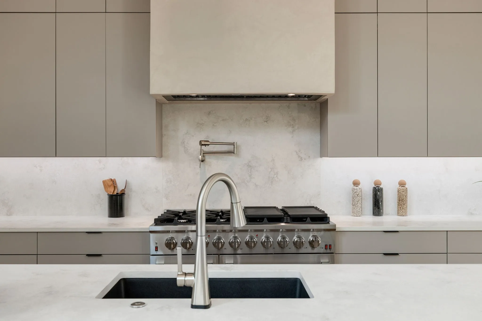 Modern kitchen featuring a stainless steel range with griddle, pot filler, and custom range hood