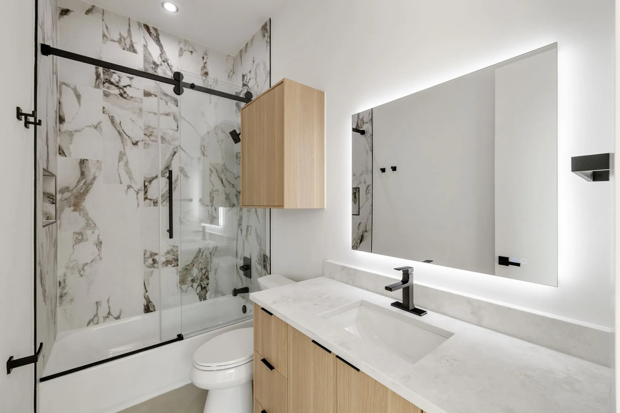 Modern bathroom featuring a single vanity with wood-finish cabinetry, a white countertop, and a rectangular undermount sink