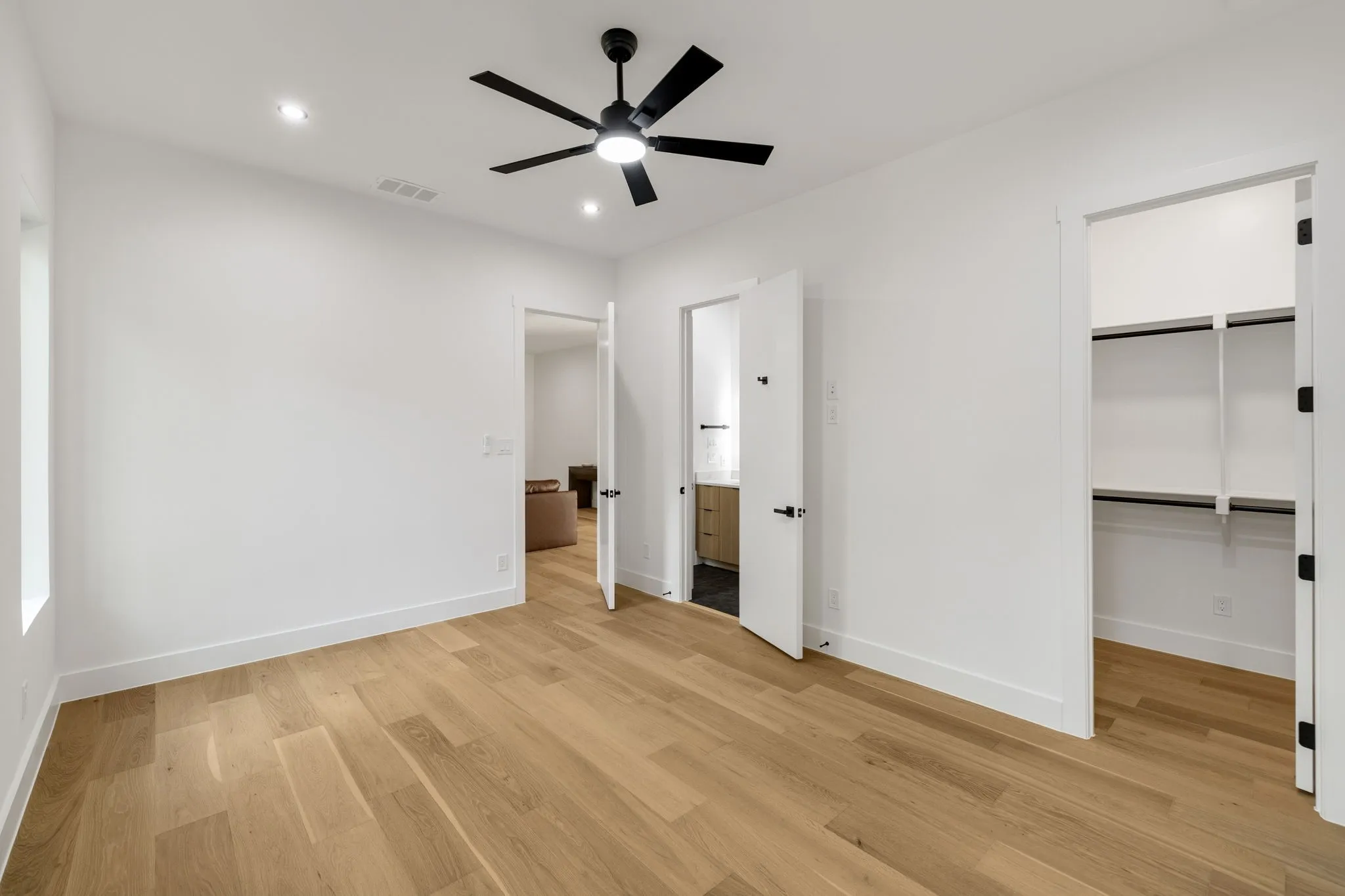Bright interior space featuring wood-finish flooring, recessed lighting, and a contemporary ceiling fan