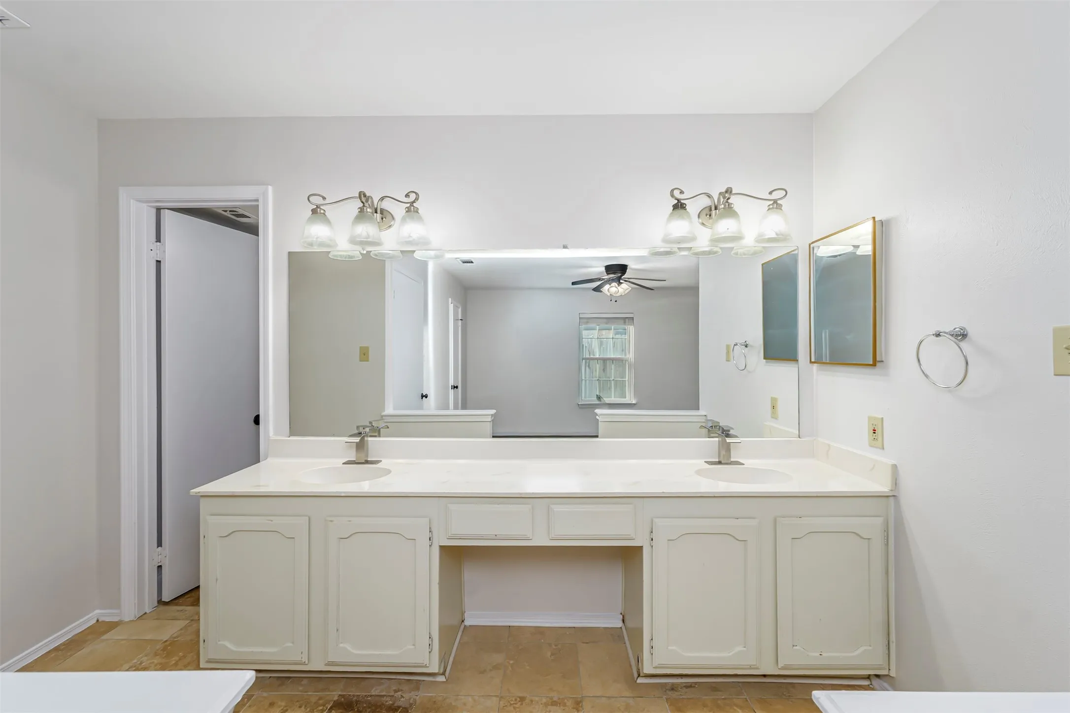 Double vanity with integrated sinks, brushed nickel faucets, and an expansive wall-mounted mirror