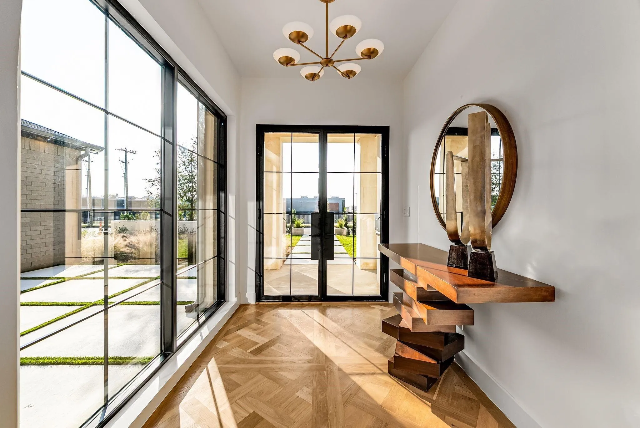 Entryway featuring herringbone wood-finish flooring, full-height windows, a grid-pattern glass door, and a modern ceiling light fixture