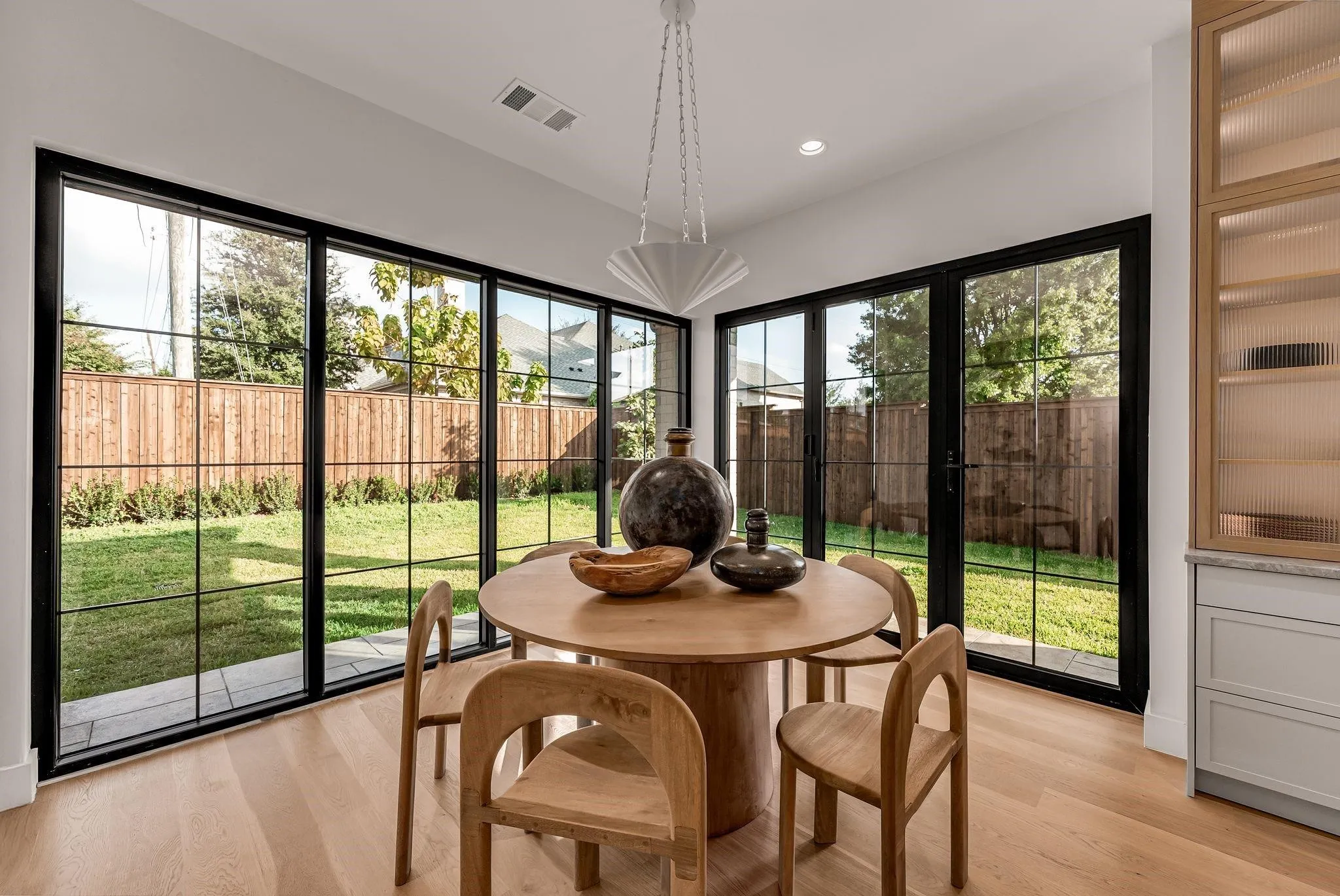 Dining area featuring large-pane black-framed windows and a coordinating glass-paneled door