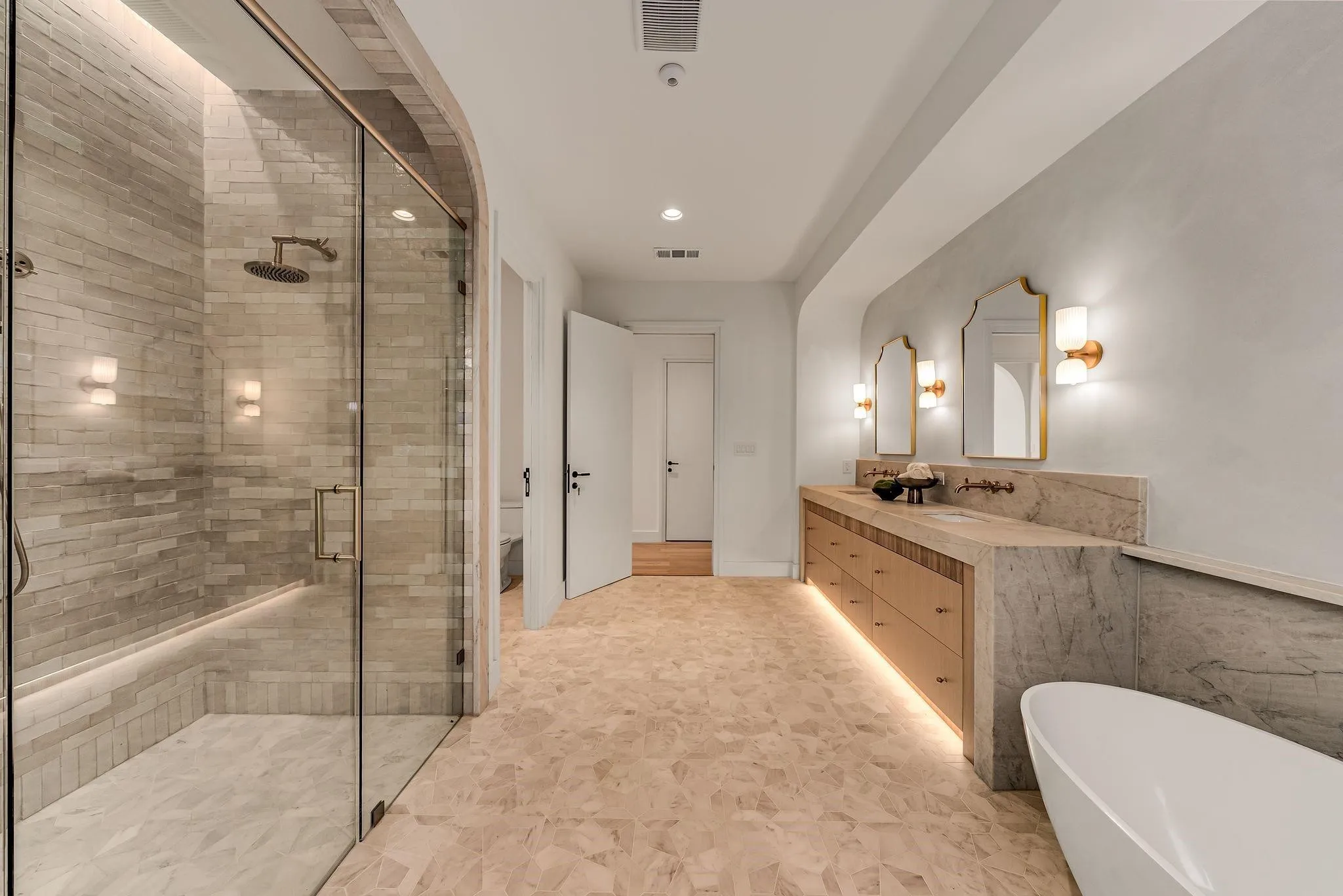 Spacious bathroom featuring a glass-enclosed shower with subway tile, dual vanity with undermount sinks, wood-finish cabinetry, and a freestanding bathtub