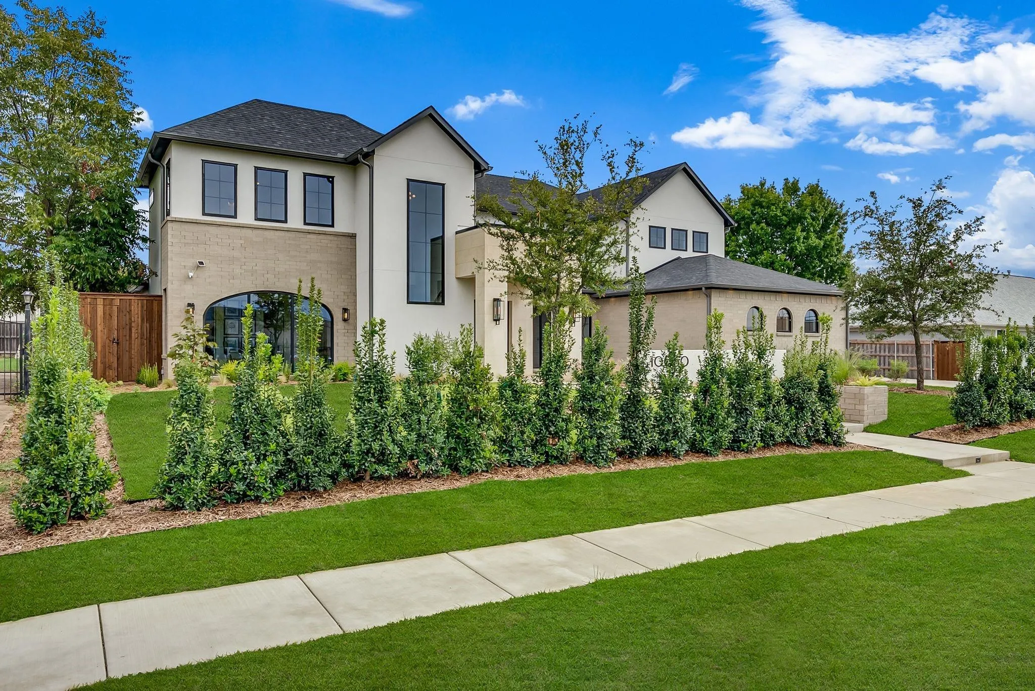 Contemporary residence featuring a light-colored stucco and brick facade with dark-framed windows