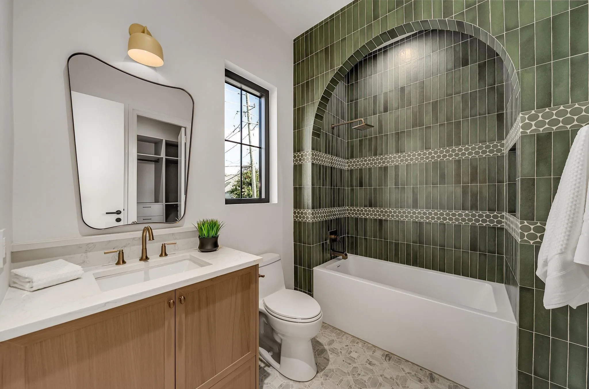 Bathroom featuring a deep soaking tub within an arched, vertically tiled shower enclosure