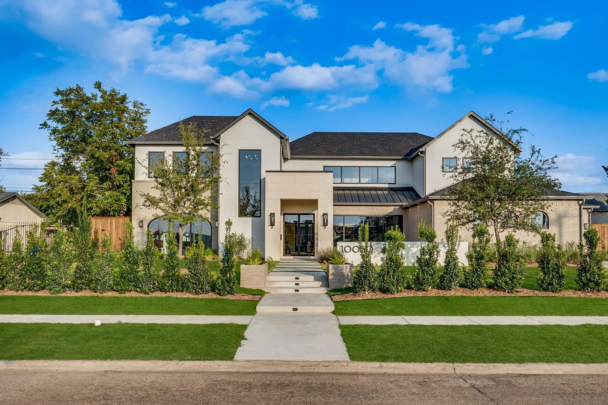 Contemporary facade with a combination of light-colored stucco and brick veneer, featuring a dark shingle roof