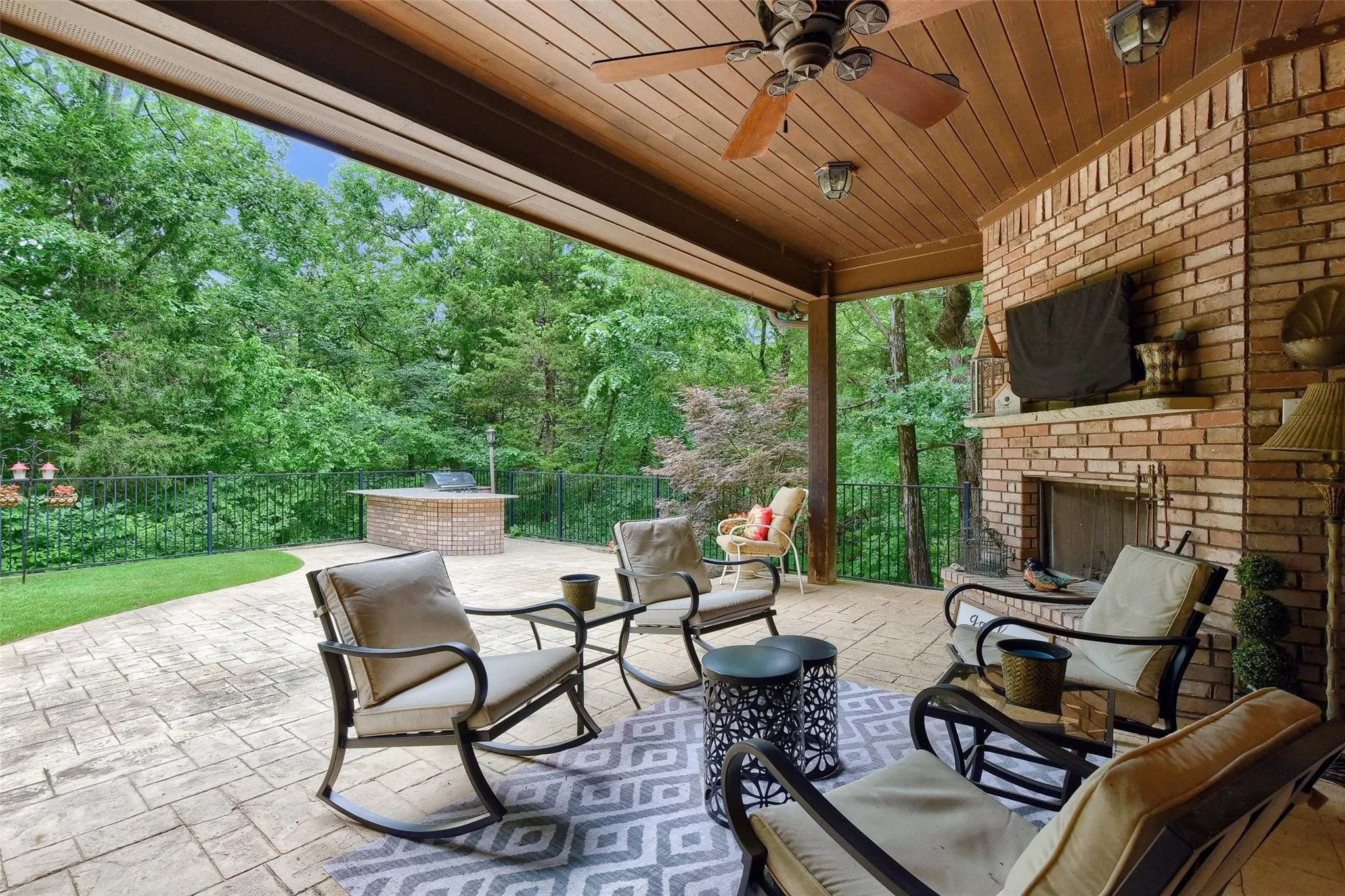 Covered outdoor living area featuring a brick fireplace