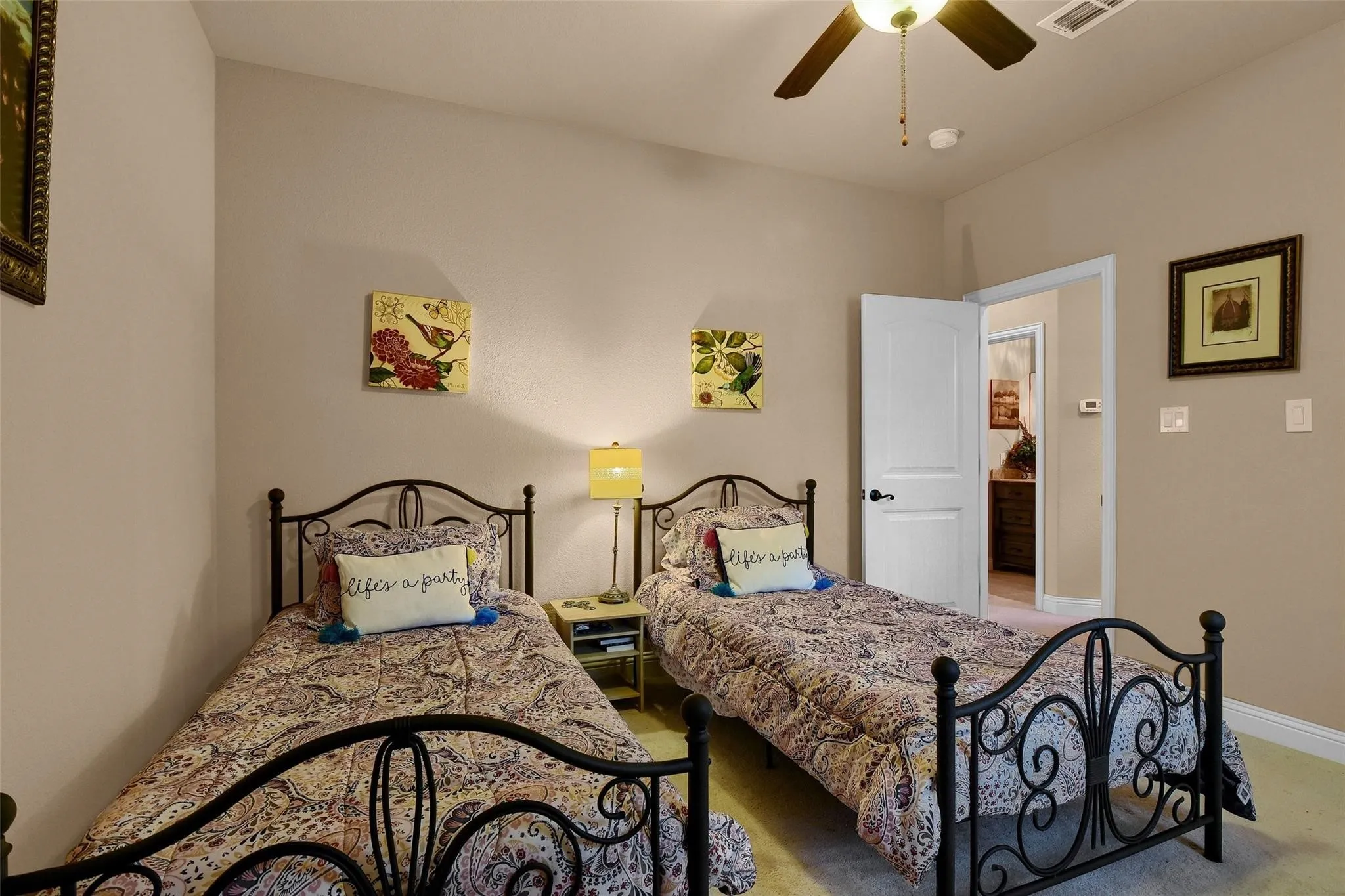 Carpeted room featuring a ceiling fan, light neutral wall paint, and a white interior door