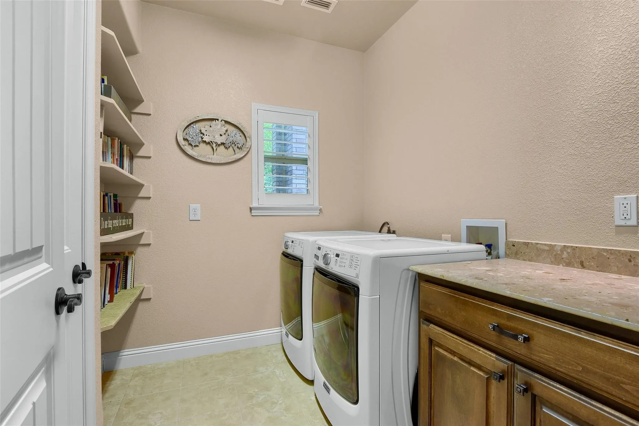 Functional utility space featuring wood-finish cabinetry, solid surface countertop, and multiple built-in shelving units