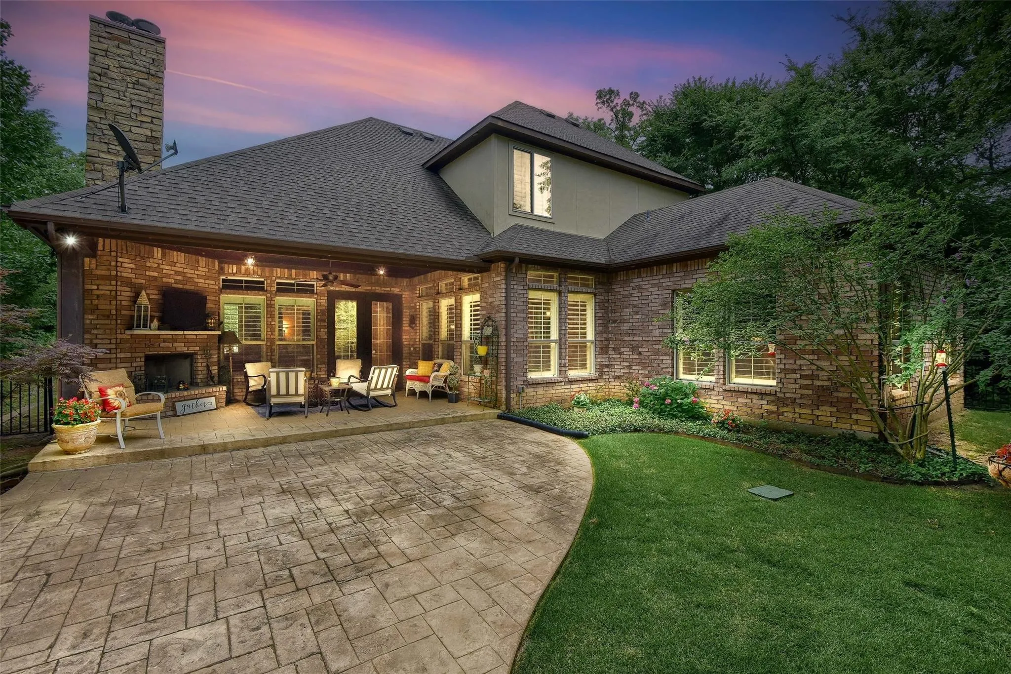 Expansive stamped concrete patio featuring a covered outdoor living area with a stone-clad fireplace and integrated lighting
