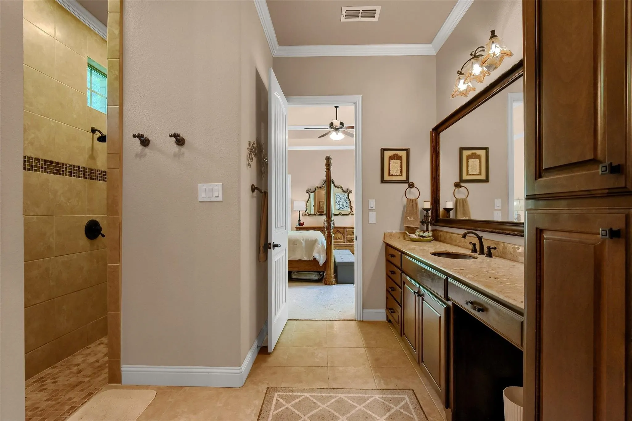 Bathroom featuring a tiled walk-in shower with a decorative accent band, a vanity with an integrated sink and stone countertop, dark wood-finish cabinetry, and a large framed mirror
