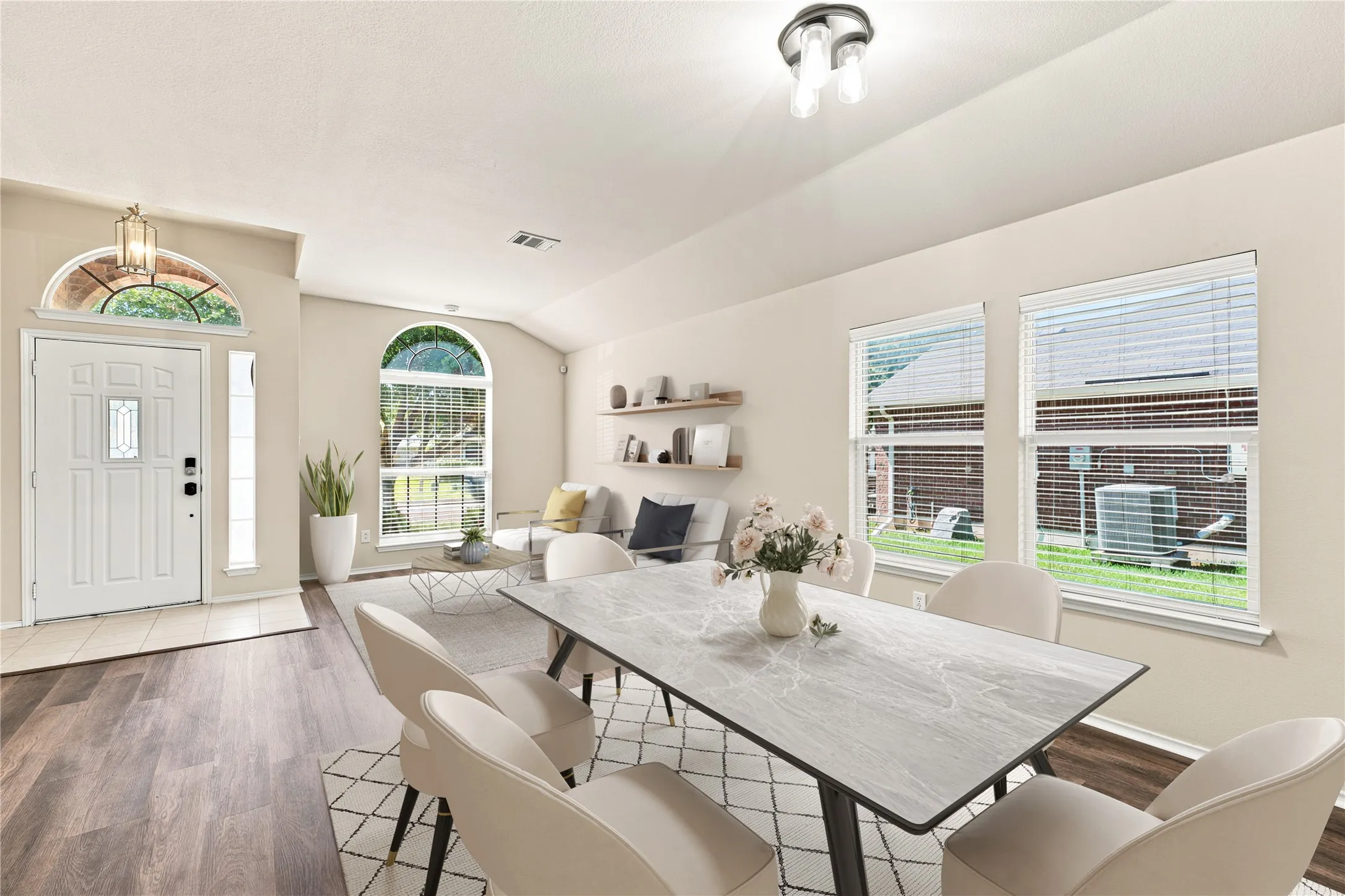 Combined dining and living area featuring wood-finish flooring, vaulted ceilings, and a light color palette