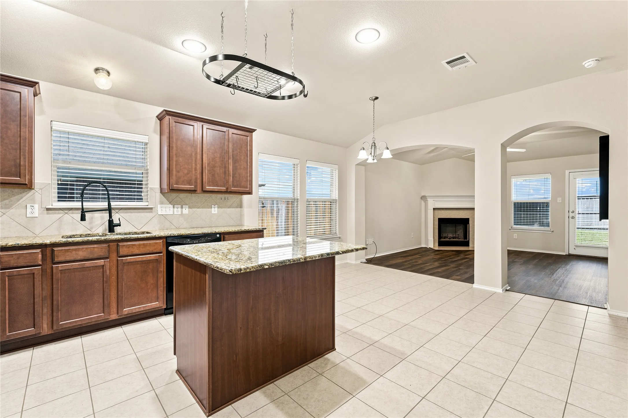 Kitchen featuring a central island, wood-finish cabinetry, granite countertops, and a tile backsplash