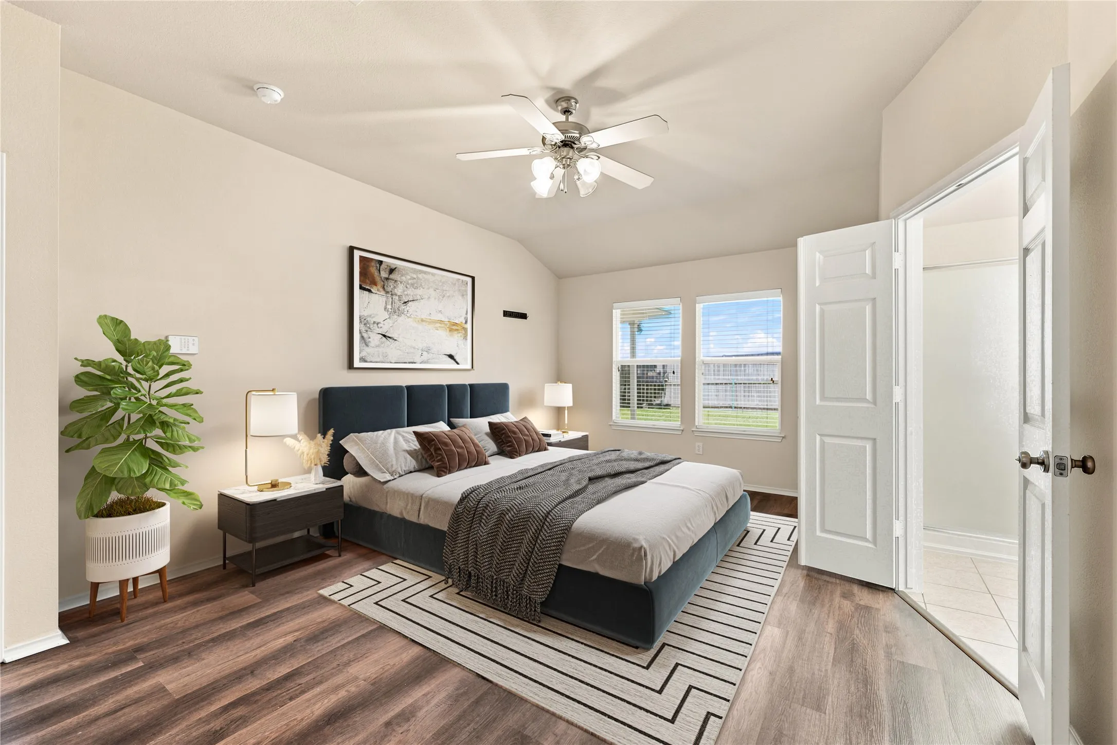 Spacious bedroom featuring wood-finish flooring, vaulted ceiling, and a ceiling fan