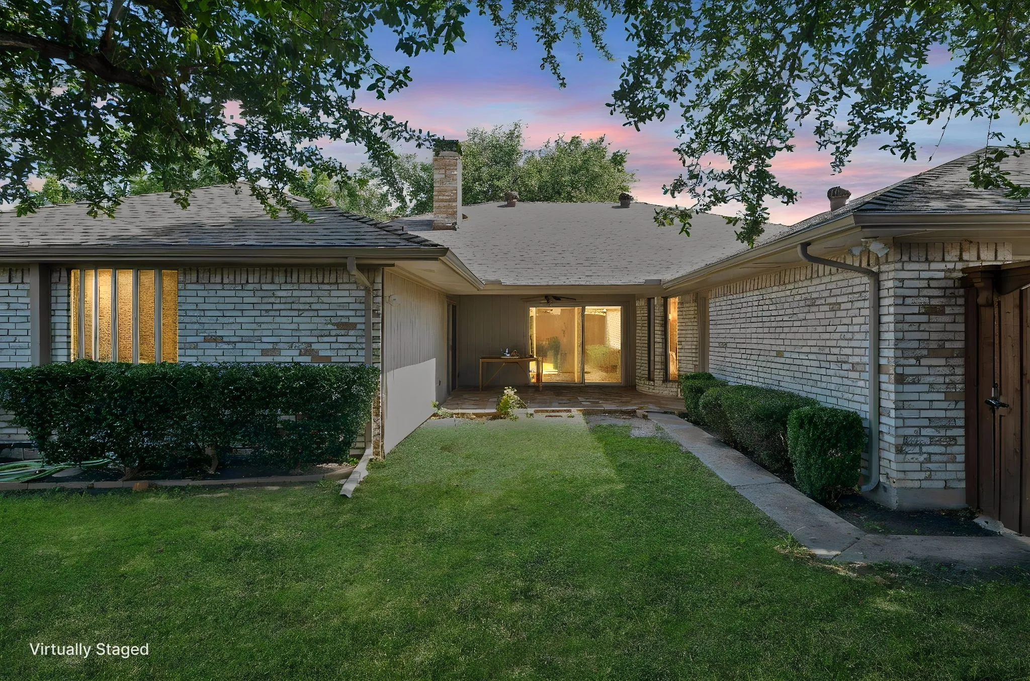 Manicured backyard featuring a concrete patio, sliding glass door, and privacy fencing