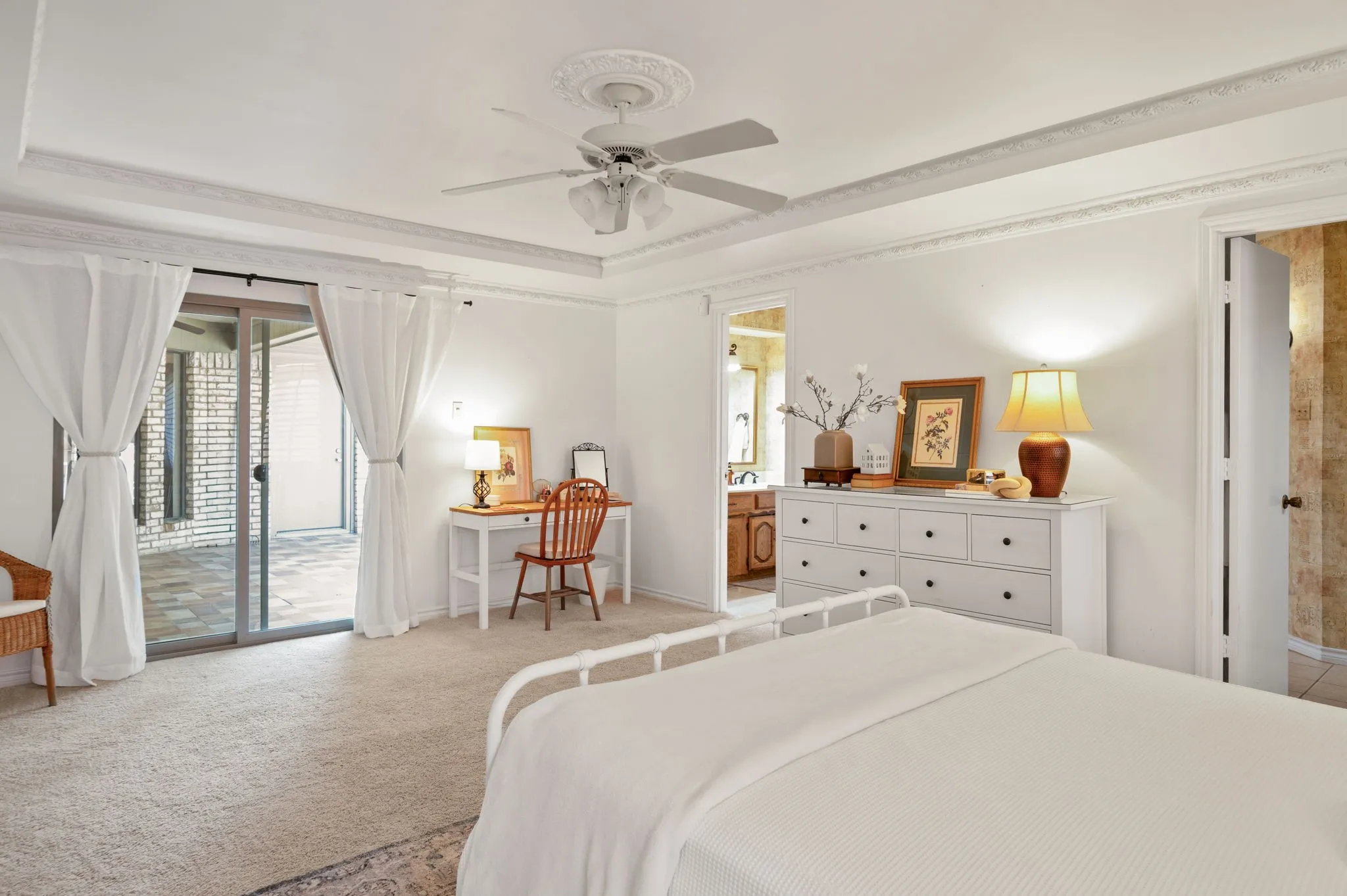Recessed ceiling with decorative molding, ceiling fan, and light-colored carpeting