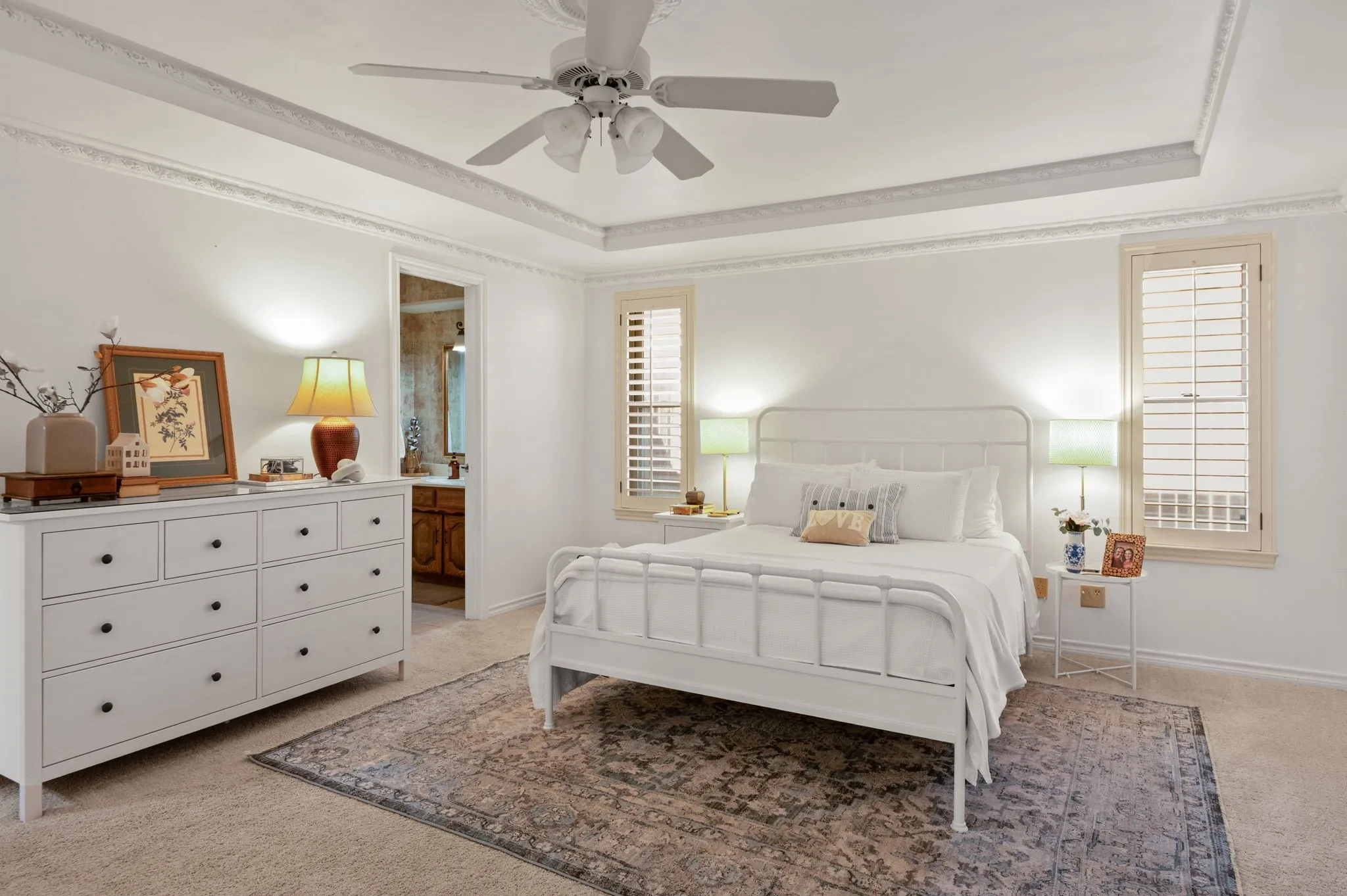 Recessed ceiling with decorative molding, ceiling fan, and carpeted flooring