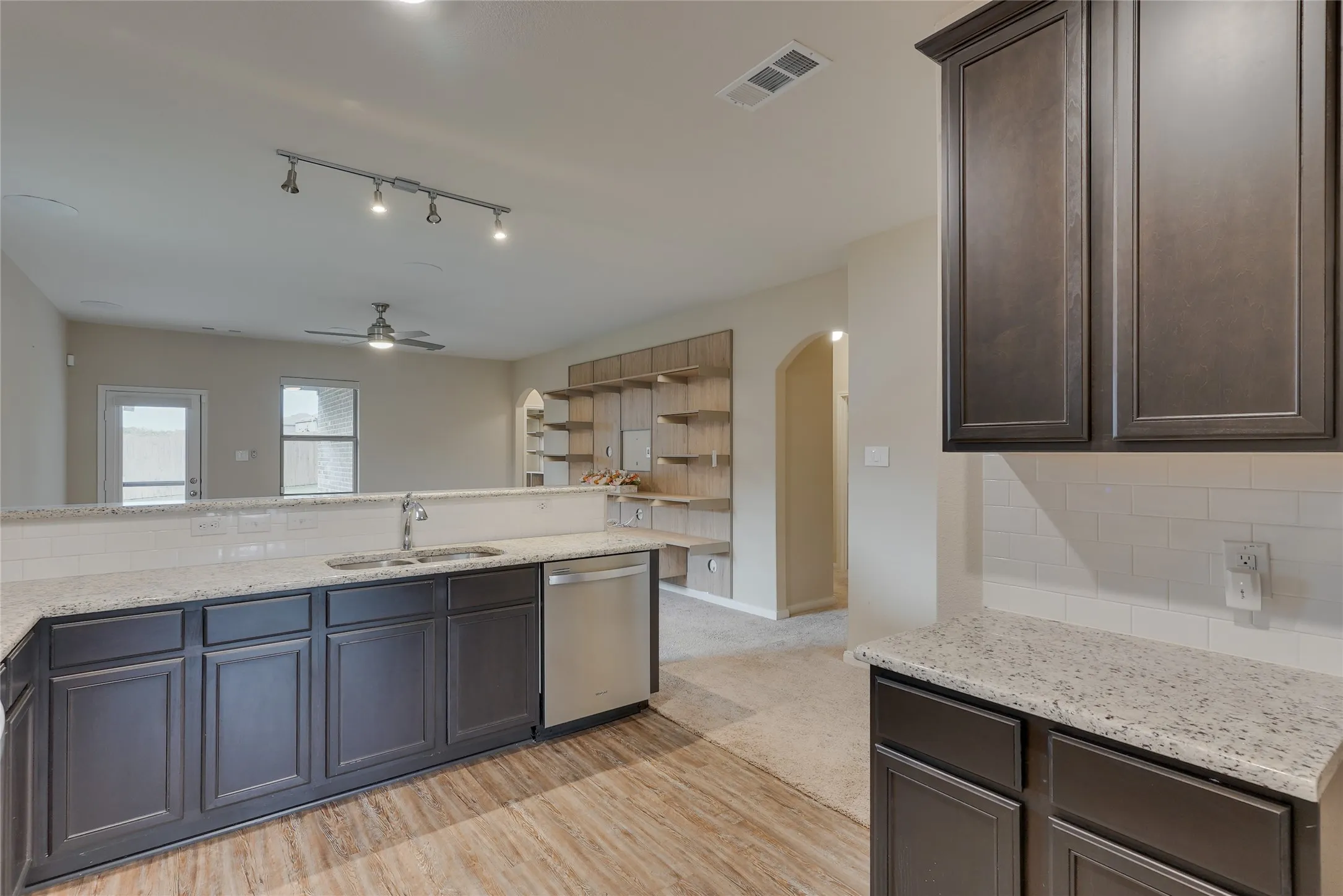 Kitchen featuring dark wood-finish cabinetry, light speckled countertops, and a subway tile backsplash