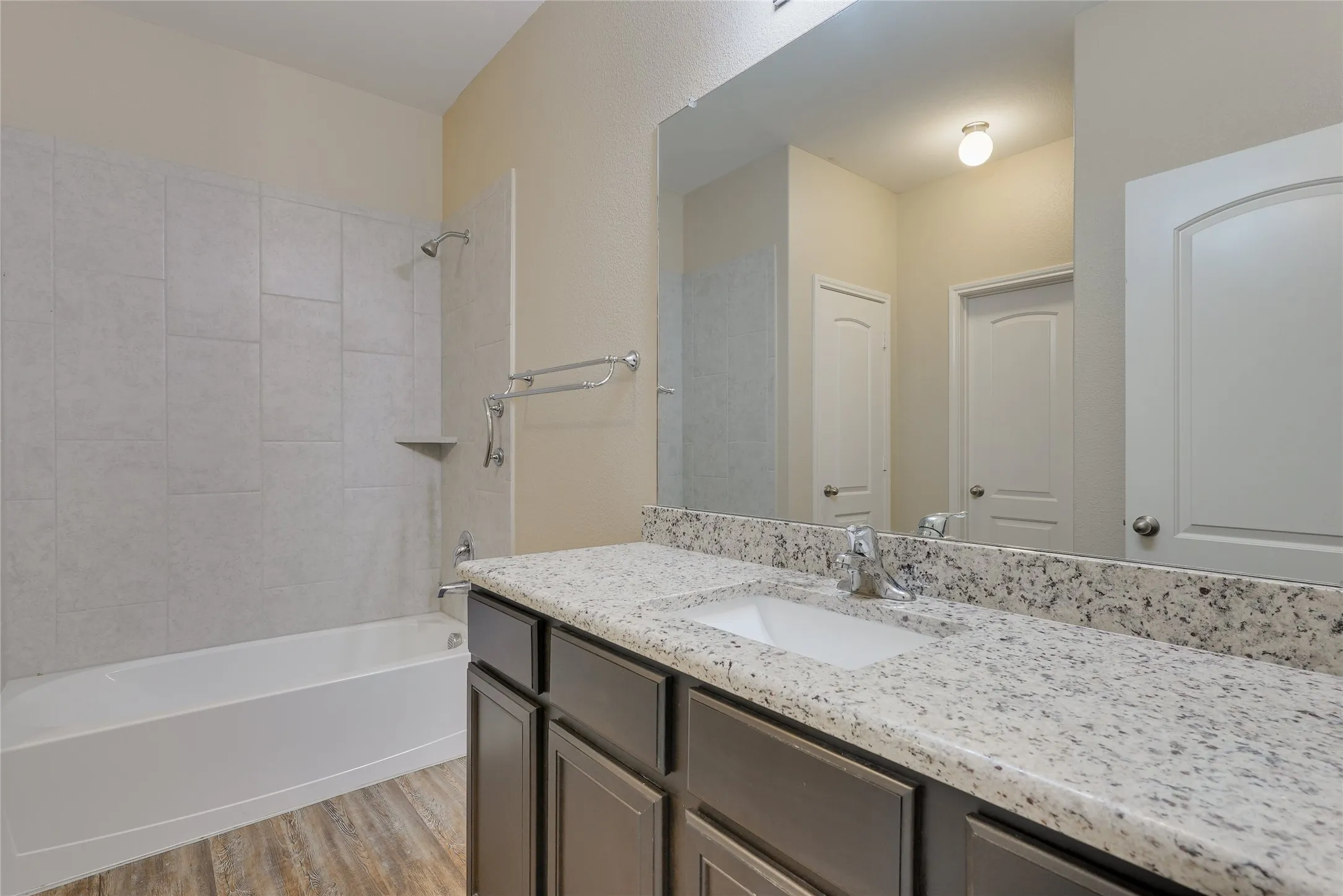 Bathroom vanity featuring a speckled countertop, undermount sink, and dark wood cabinetry