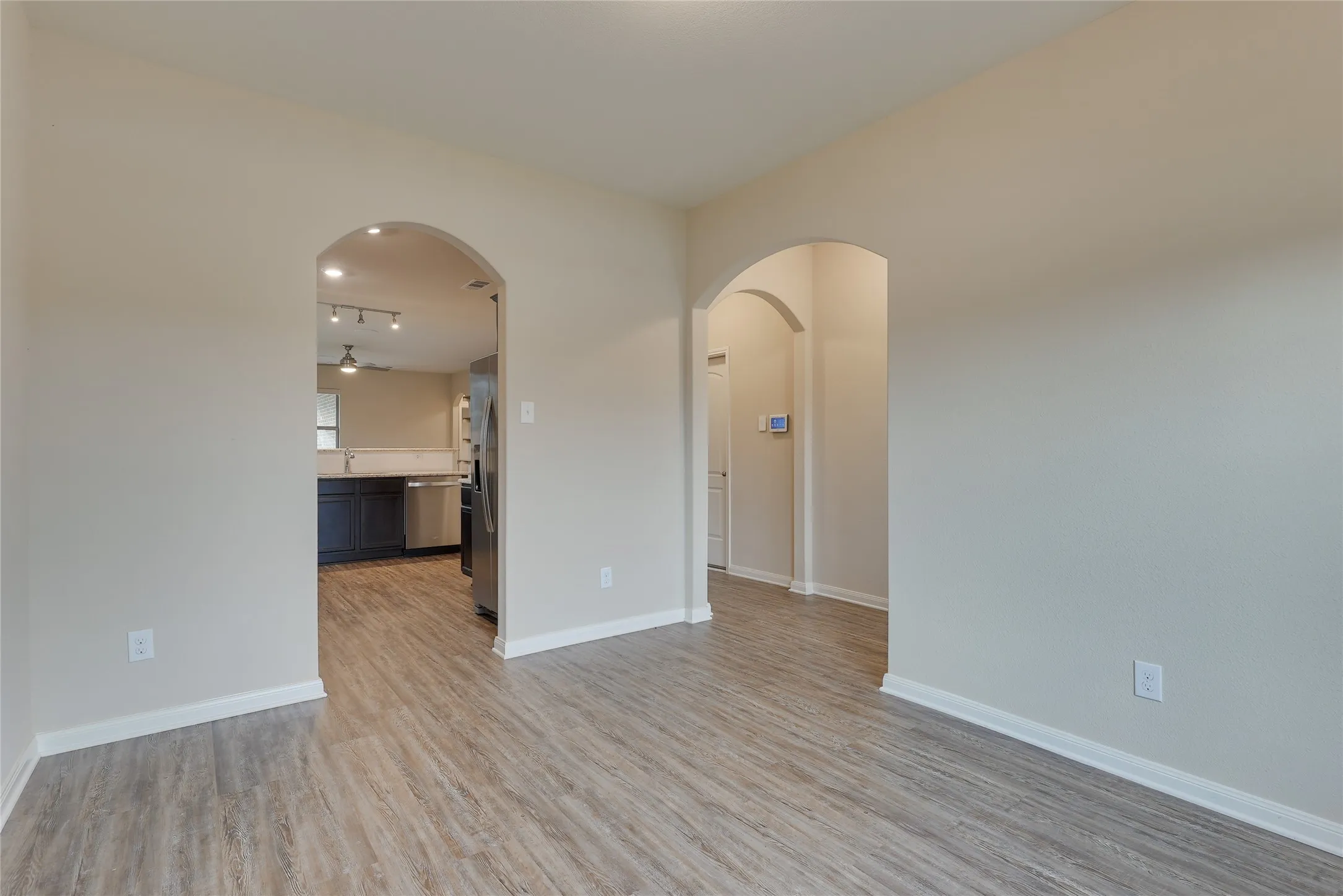 Living area featuring light wood-finish flooring, neutral wall tones, and arched doorways