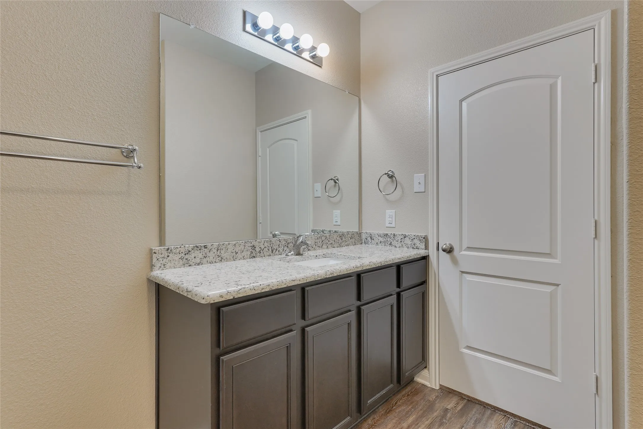 Bathroom vanity featuring a speckled countertop, undermount sink, and dark wood-finish cabinetry