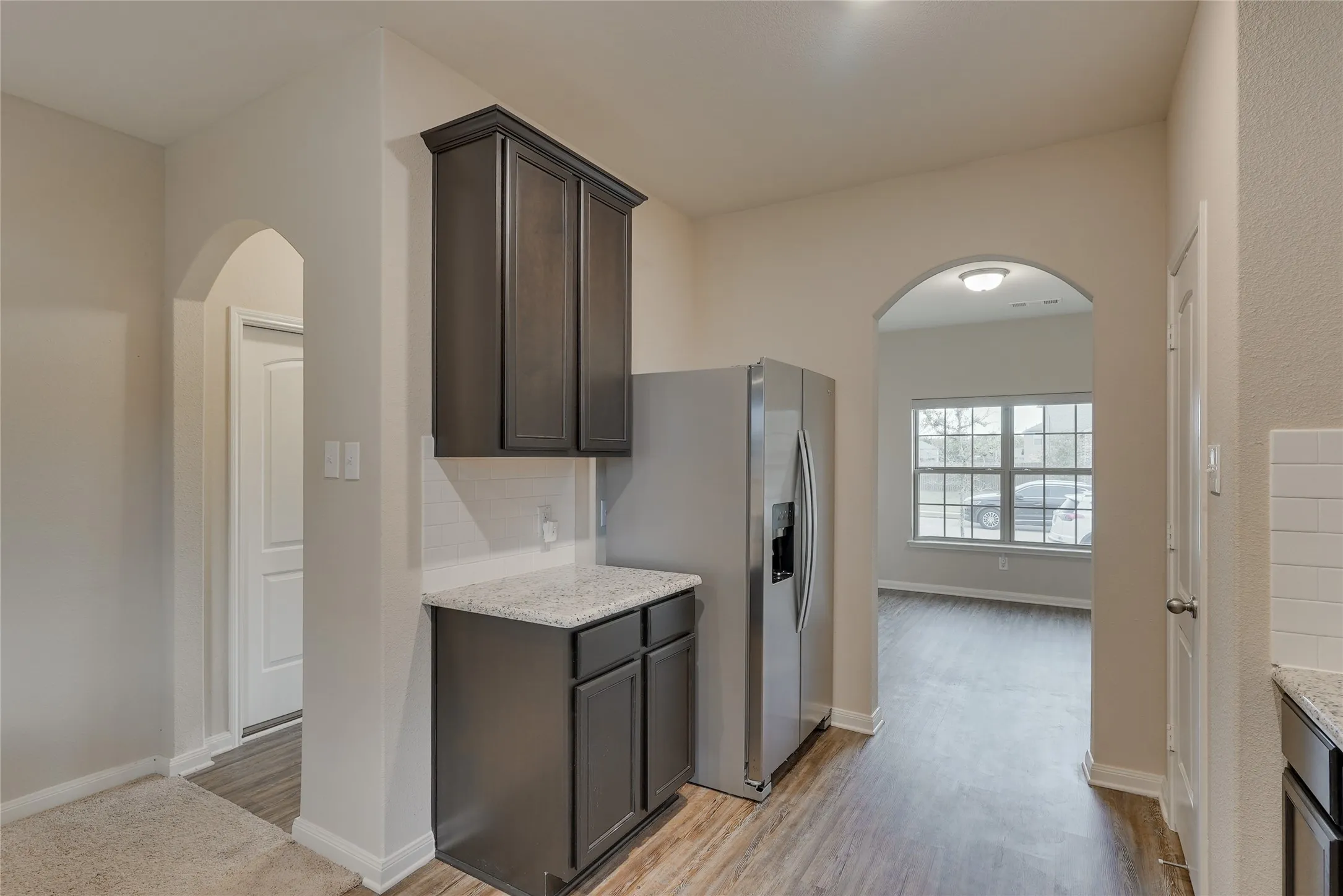 Kitchenette area featuring dark wood-finish cabinetry, a light-colored speckled countertop, and a white subway tile backsplash