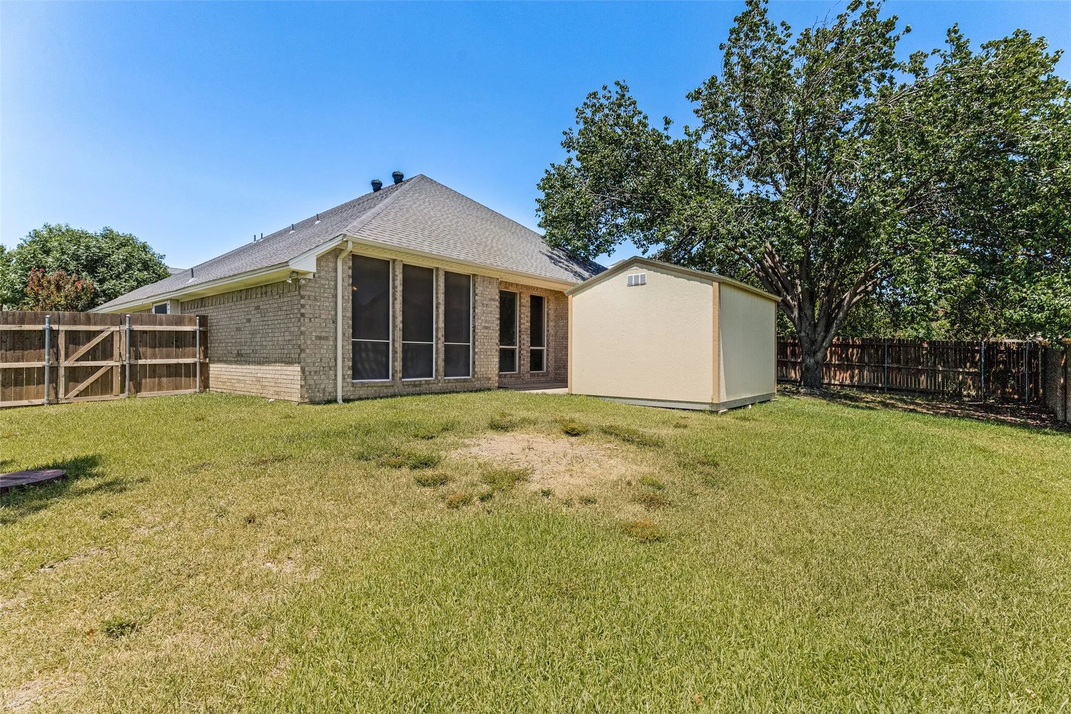 Expansive backyard featuring a detached storage shed, privacy fencing, and mature trees