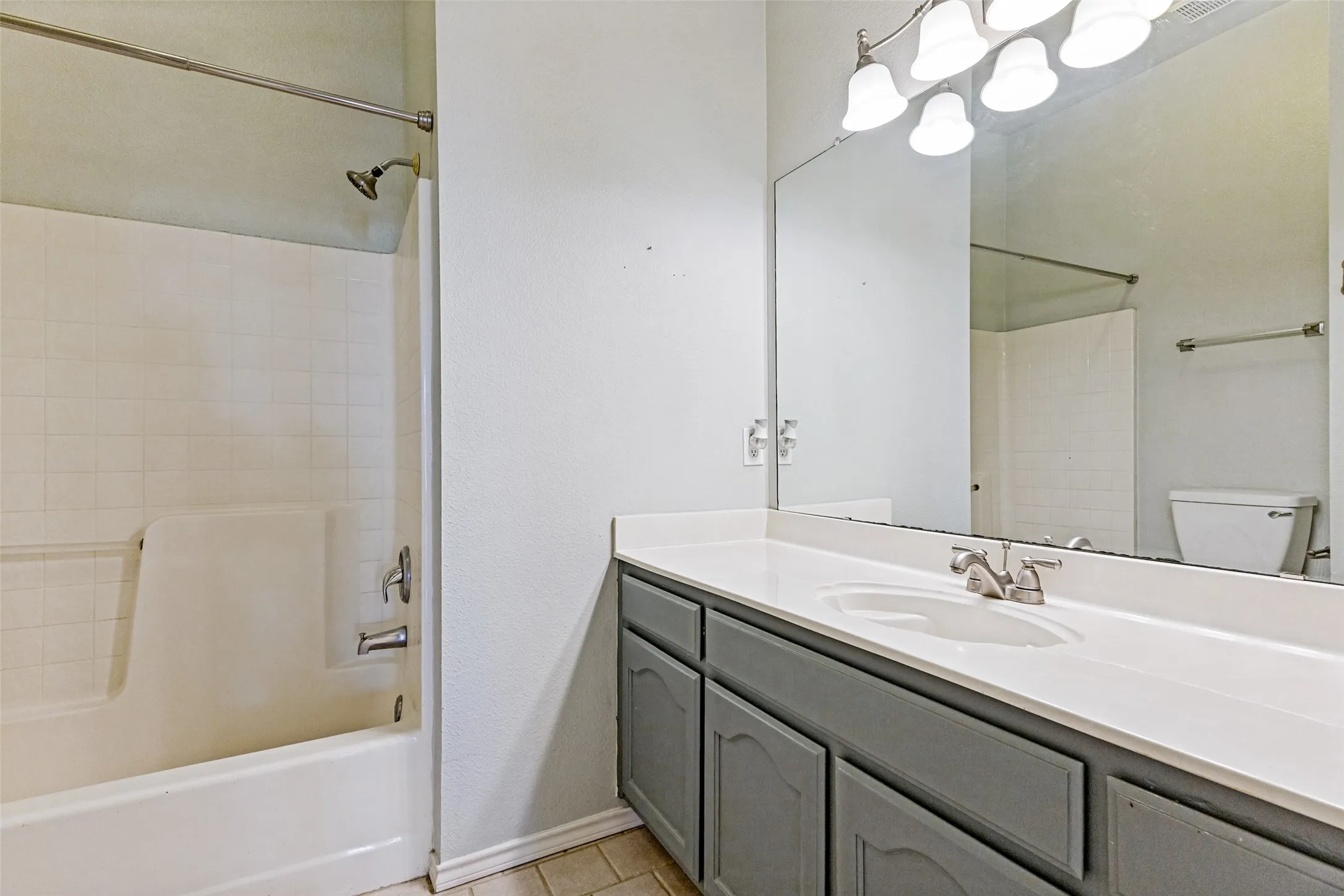 Bathroom featuring a vanity with a white countertop, an integrated sink, and gray cabinetry