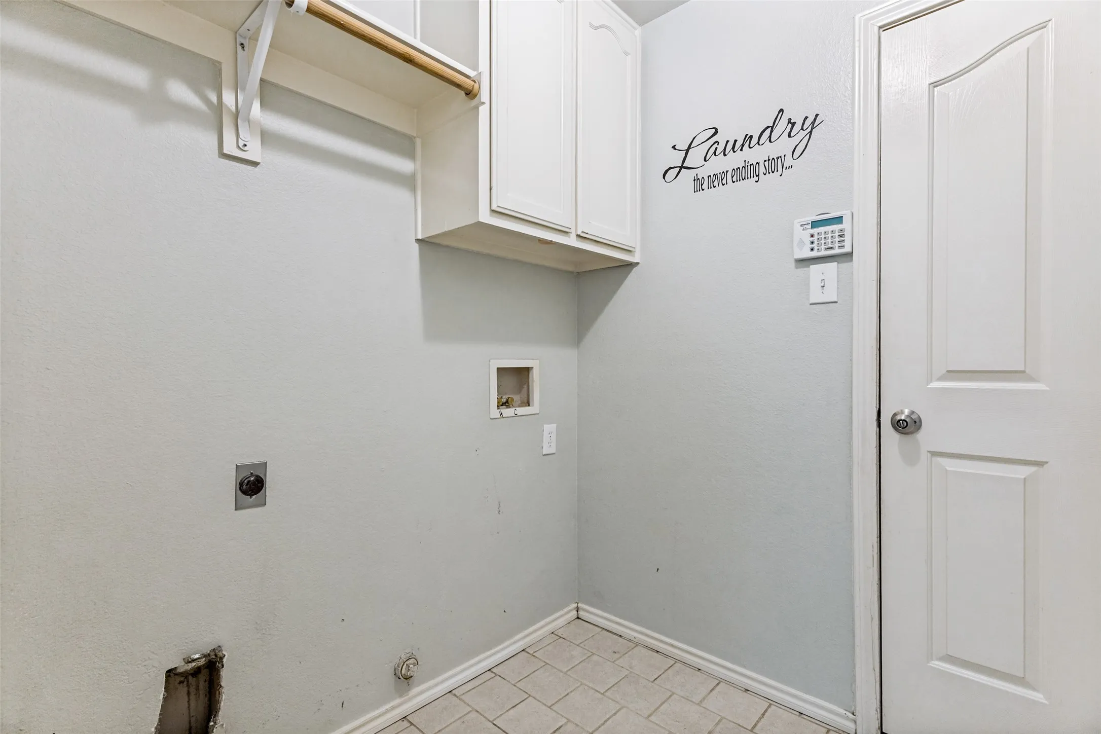 Utility area featuring overhead cabinetry, an integrated clothes rod, and tile flooring